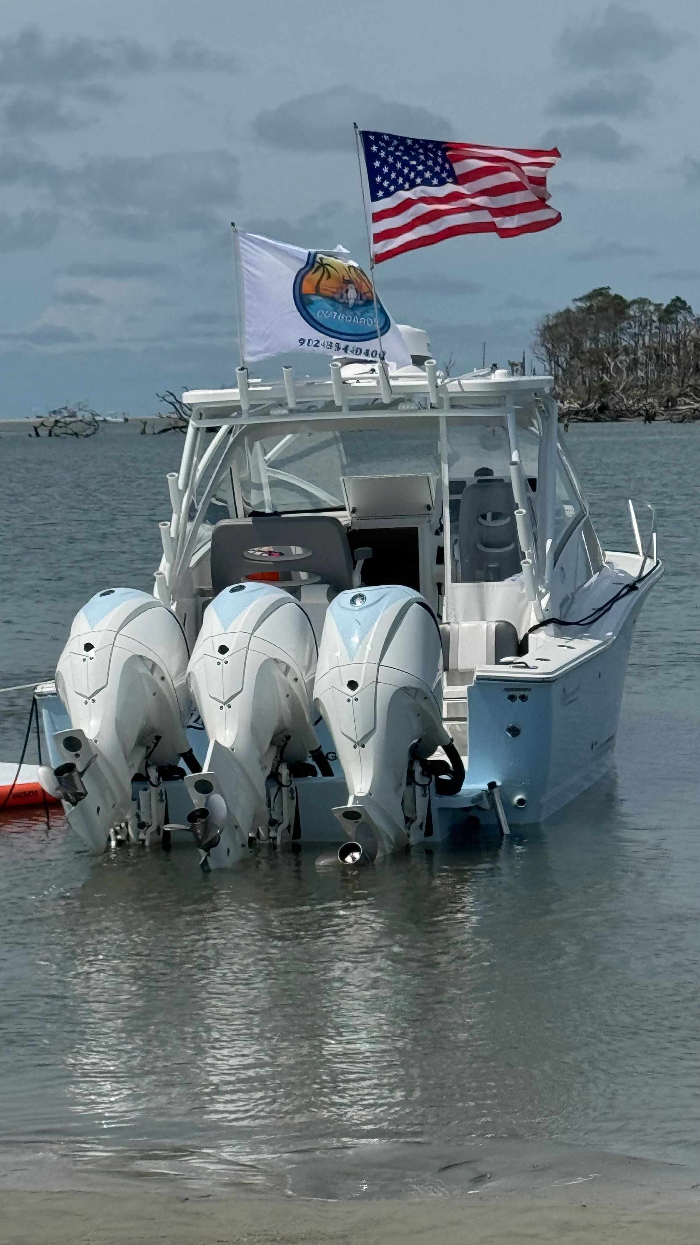 2024 Albemarle 30 Express with three outboard engines, docked at shore with flags waving.