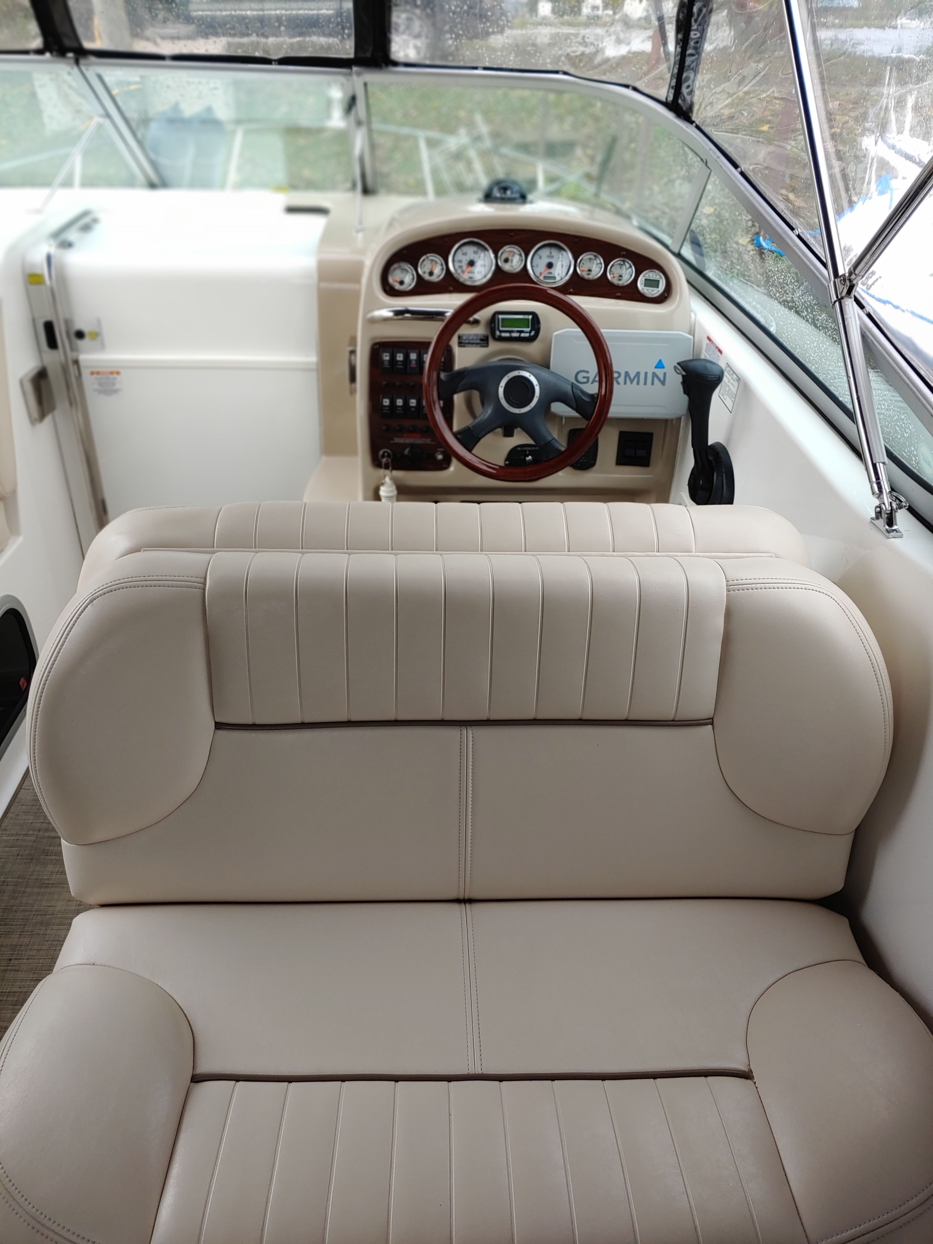 Interior of a boat with beige seating and a steering console.