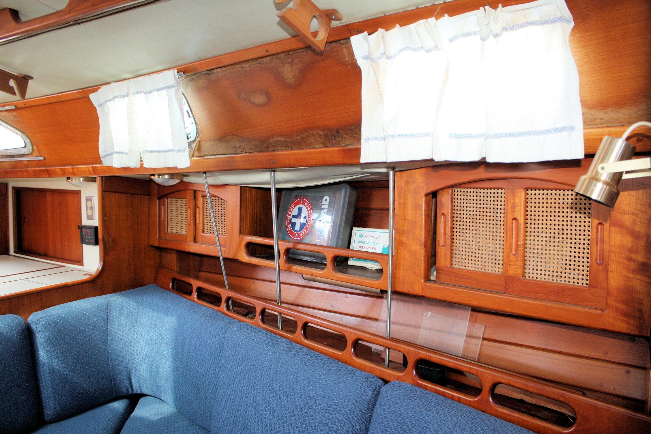 Interior of 1987 Ericson 38-200 sailboat with wooden cabinetry and blue seating.