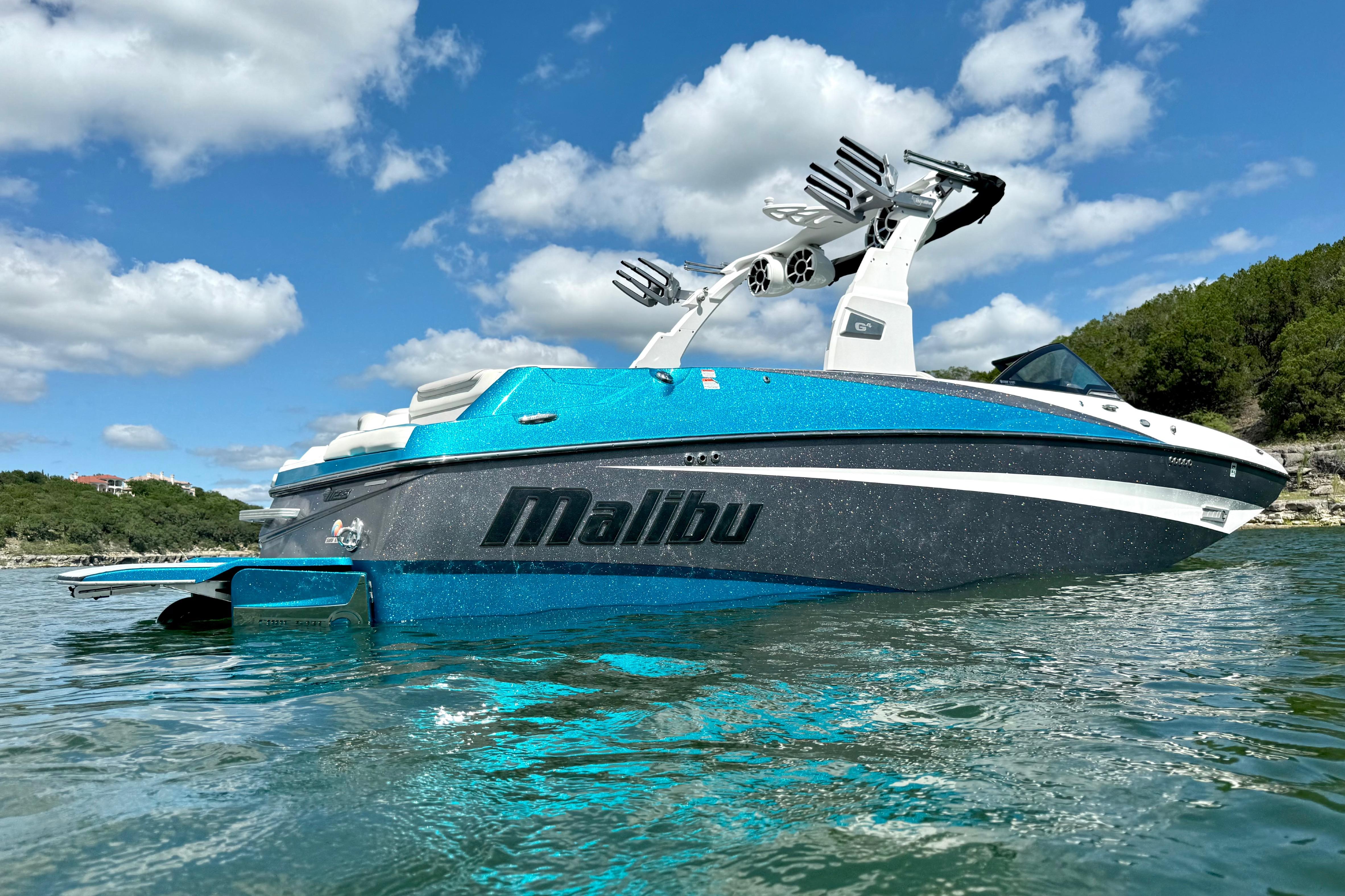 2017 Malibu M235 boat on water, blue and white design, clear sky background.