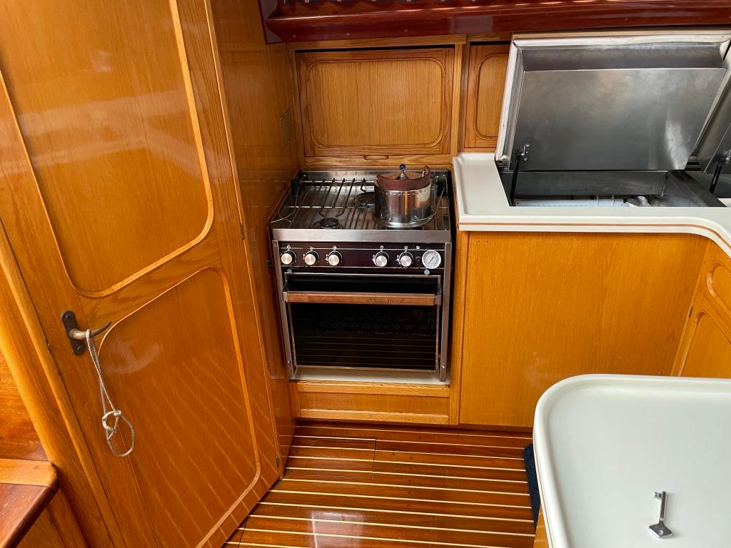 1988 Jespersen Peterson 53 yacht kitchen with wooden cabinetry and stainless steel stove.