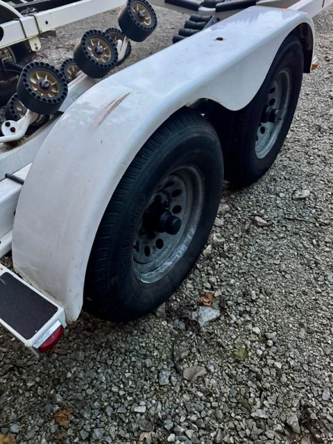 A boat trailer with two tires on a gravel surface.