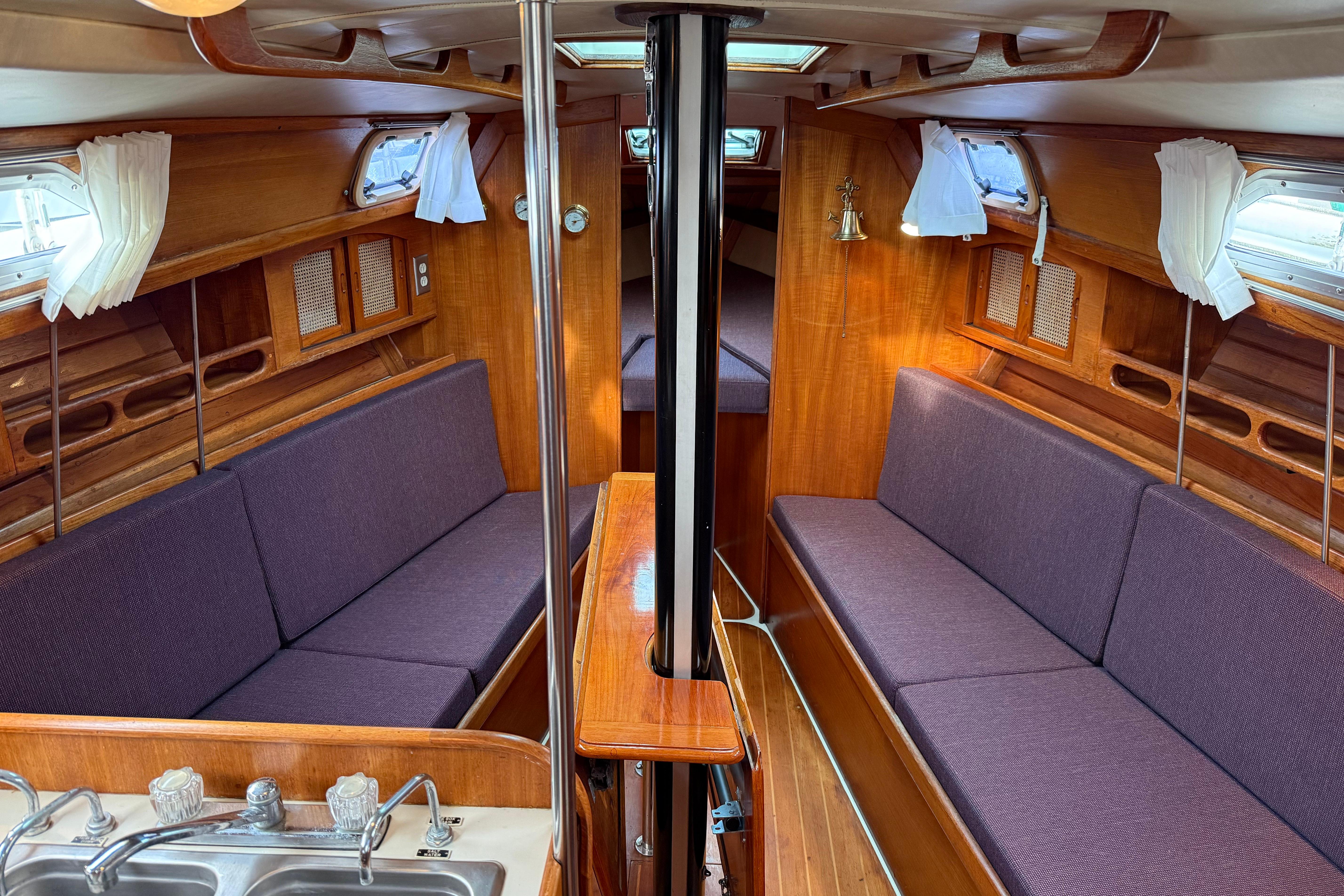 Interior of a 1988 Ericson 32-200 sailboat with wood finish and purple seating.