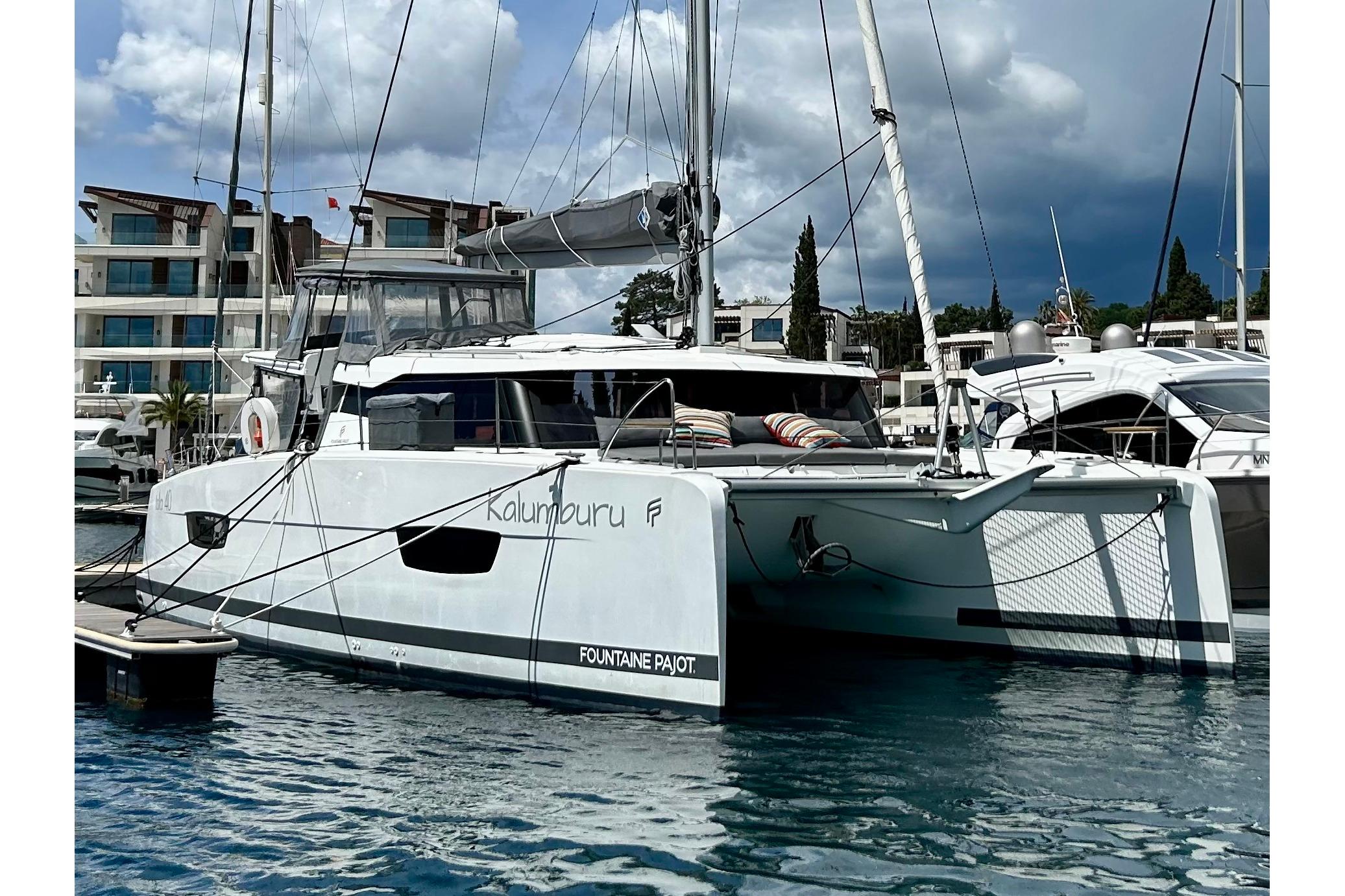 2022 Fountaine Pajot Isla 40 catamaran docked at marina, modern design, cloudy sky.