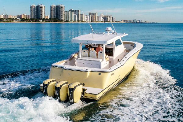 2019 Altima 38 Xcape boat cruising on calm ocean near city skyline.