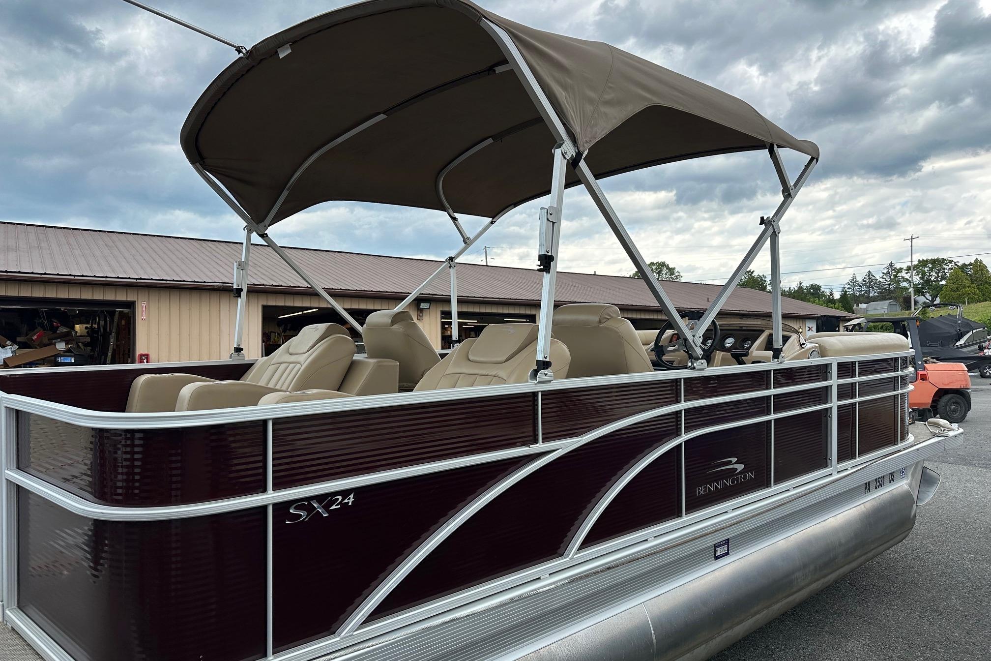 2016 Bennington 24 SCWX pontoon boat with canopy, parked outdoors under cloudy skies.