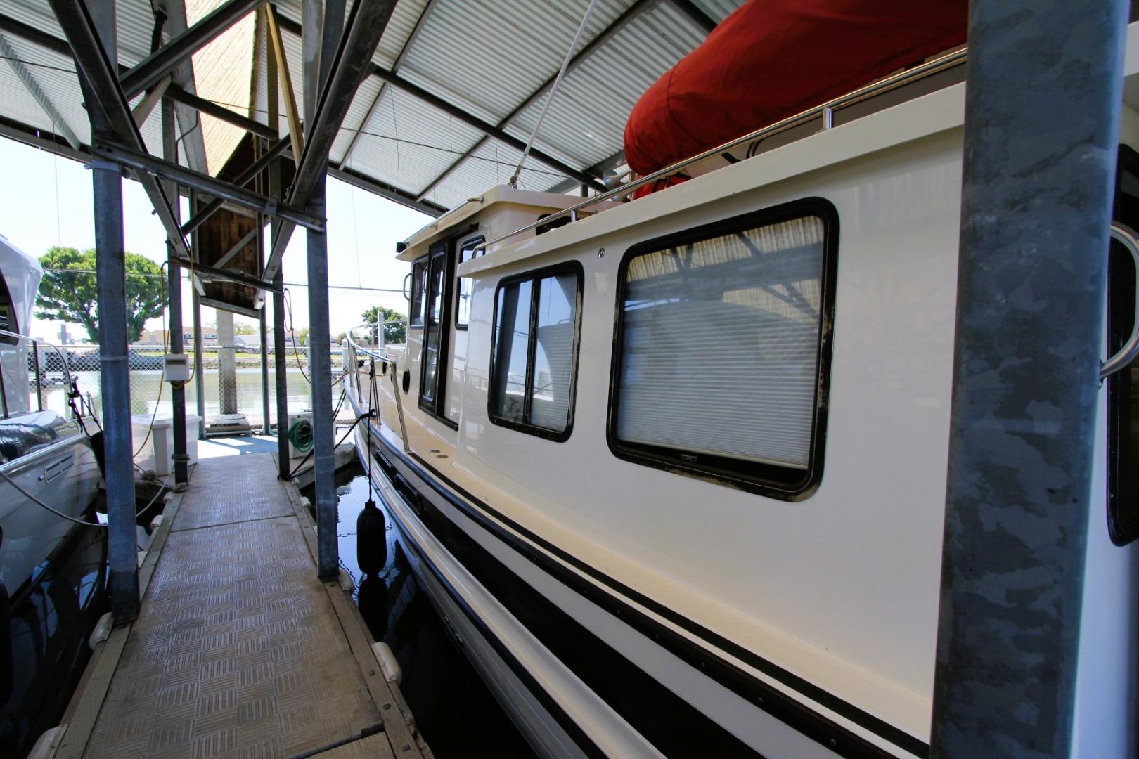2002 Nordic Tug 37 docked in a covered marina, side view.