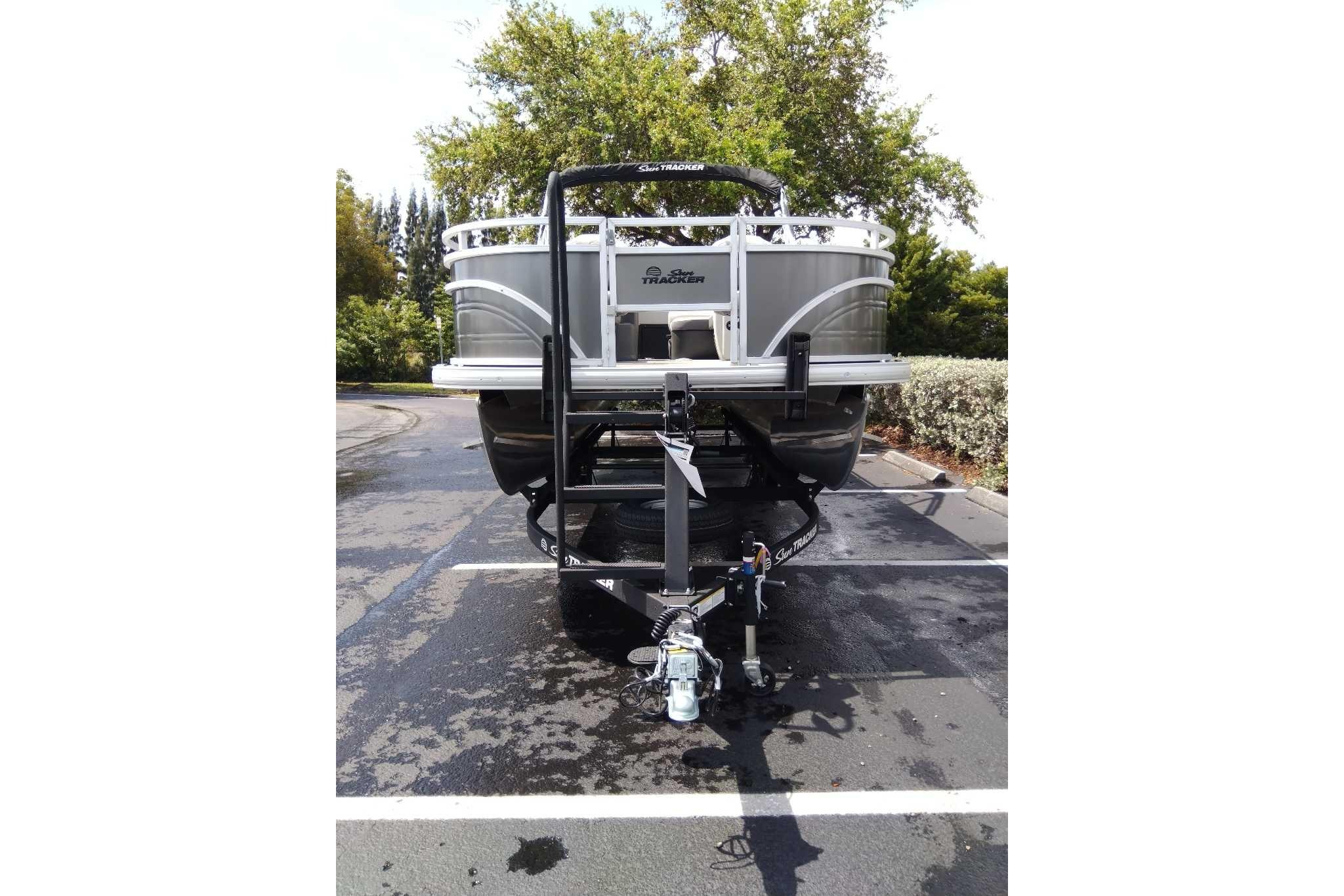 2026 Sun Tracker Fishin' Barge 22 DLX on trailer in parking lot.