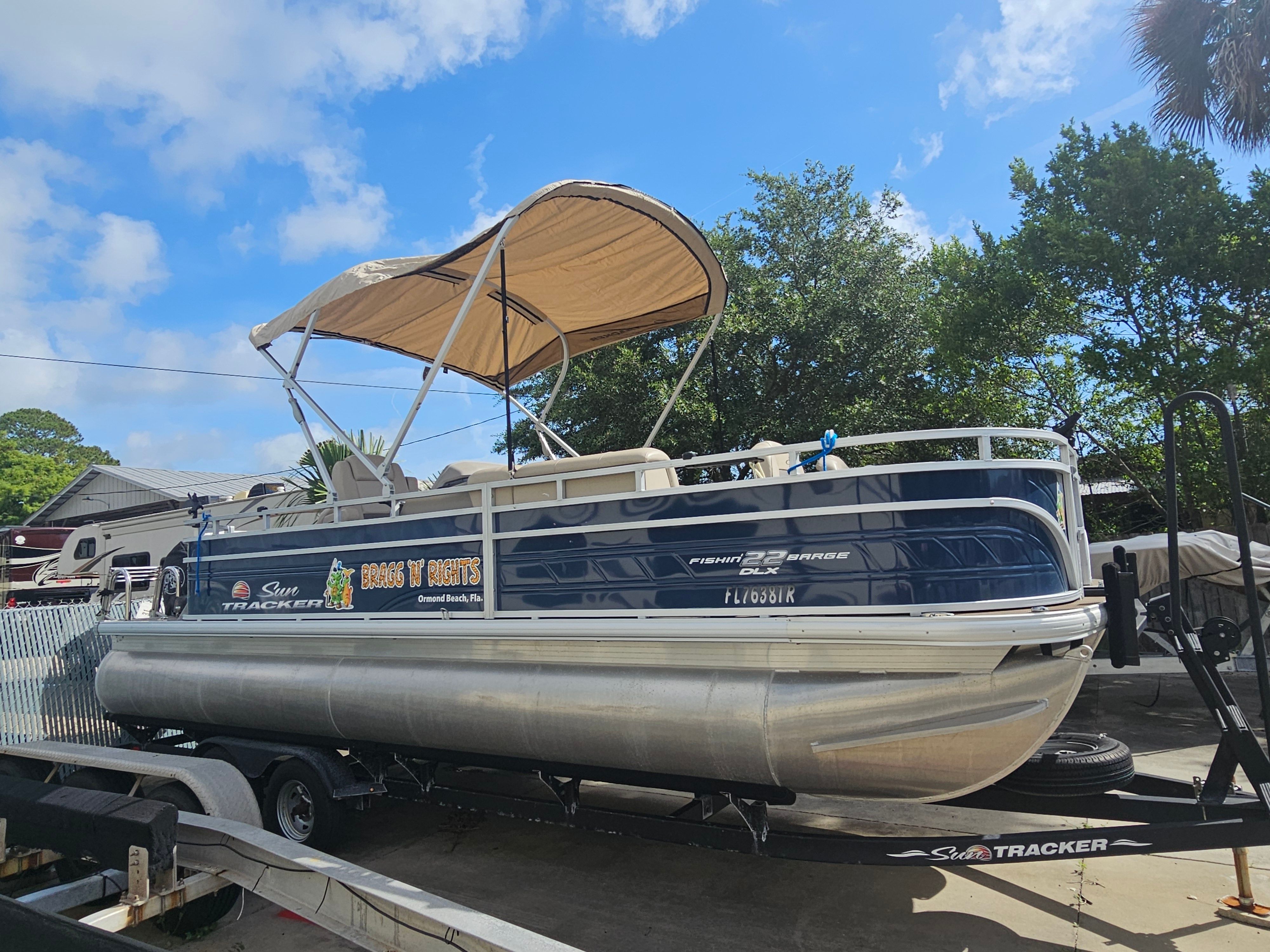 2024 Sun Tracker Fishin' Barge 22 DLX on trailer, blue sky.