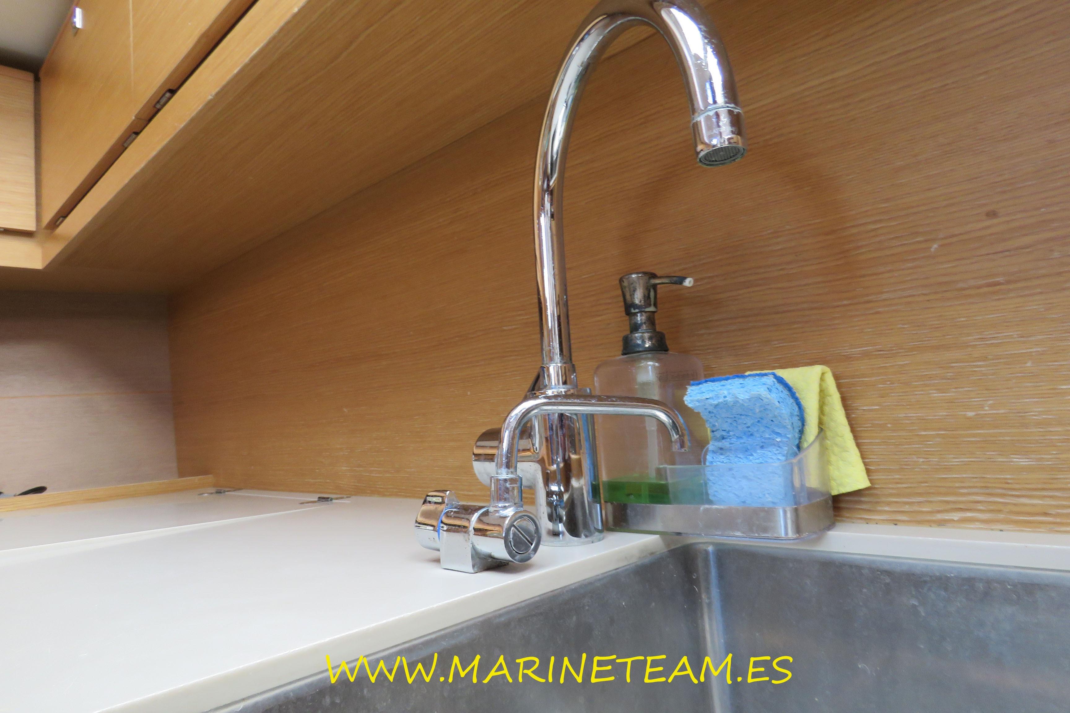 Modern kitchen sink on 2017 Dufour 460 Grand Large yacht with faucet and cleaning supplies.