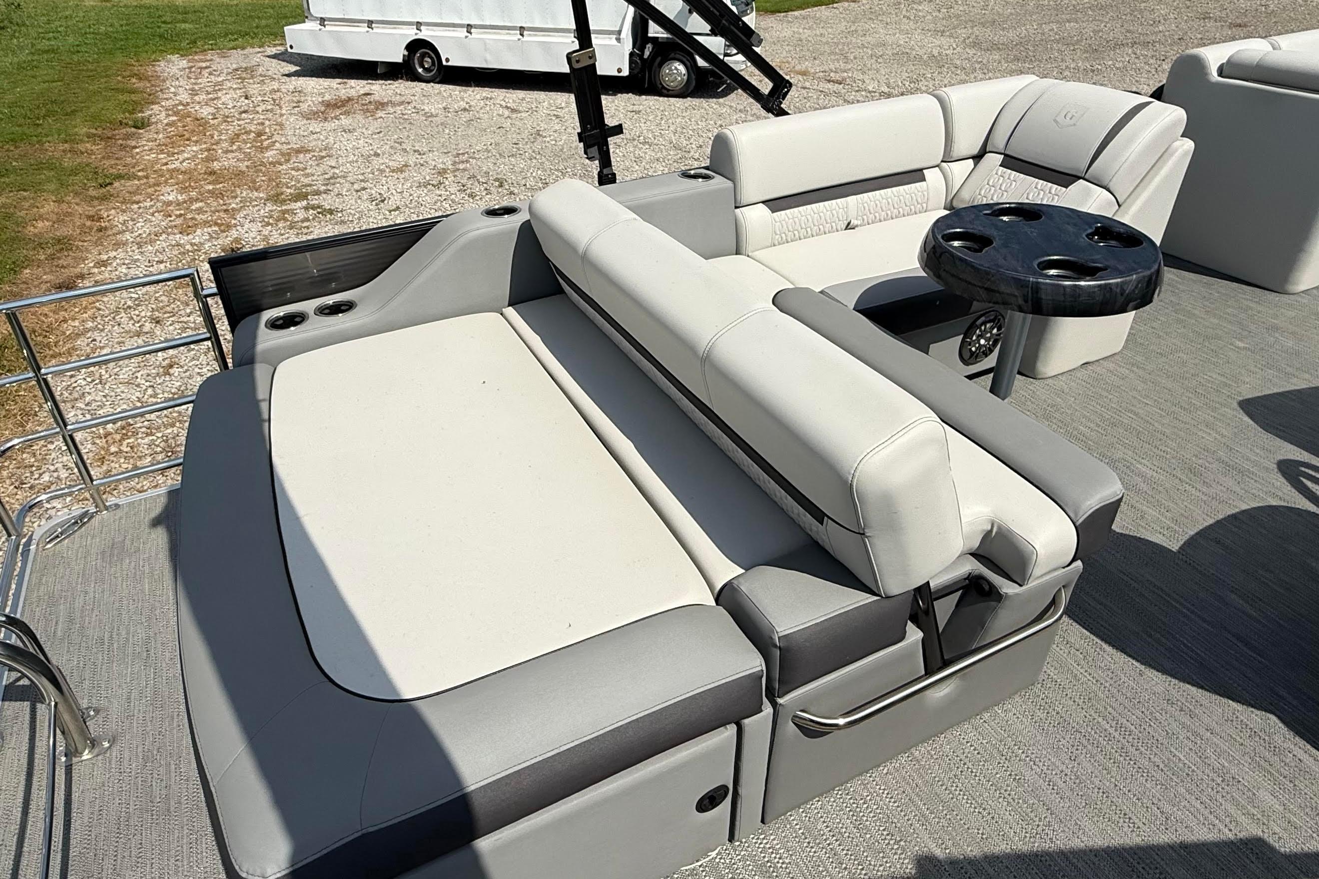 Luxurious seating on 2022 Godfrey SWEETWATER 2486 pontoon boat with cup holders and table.