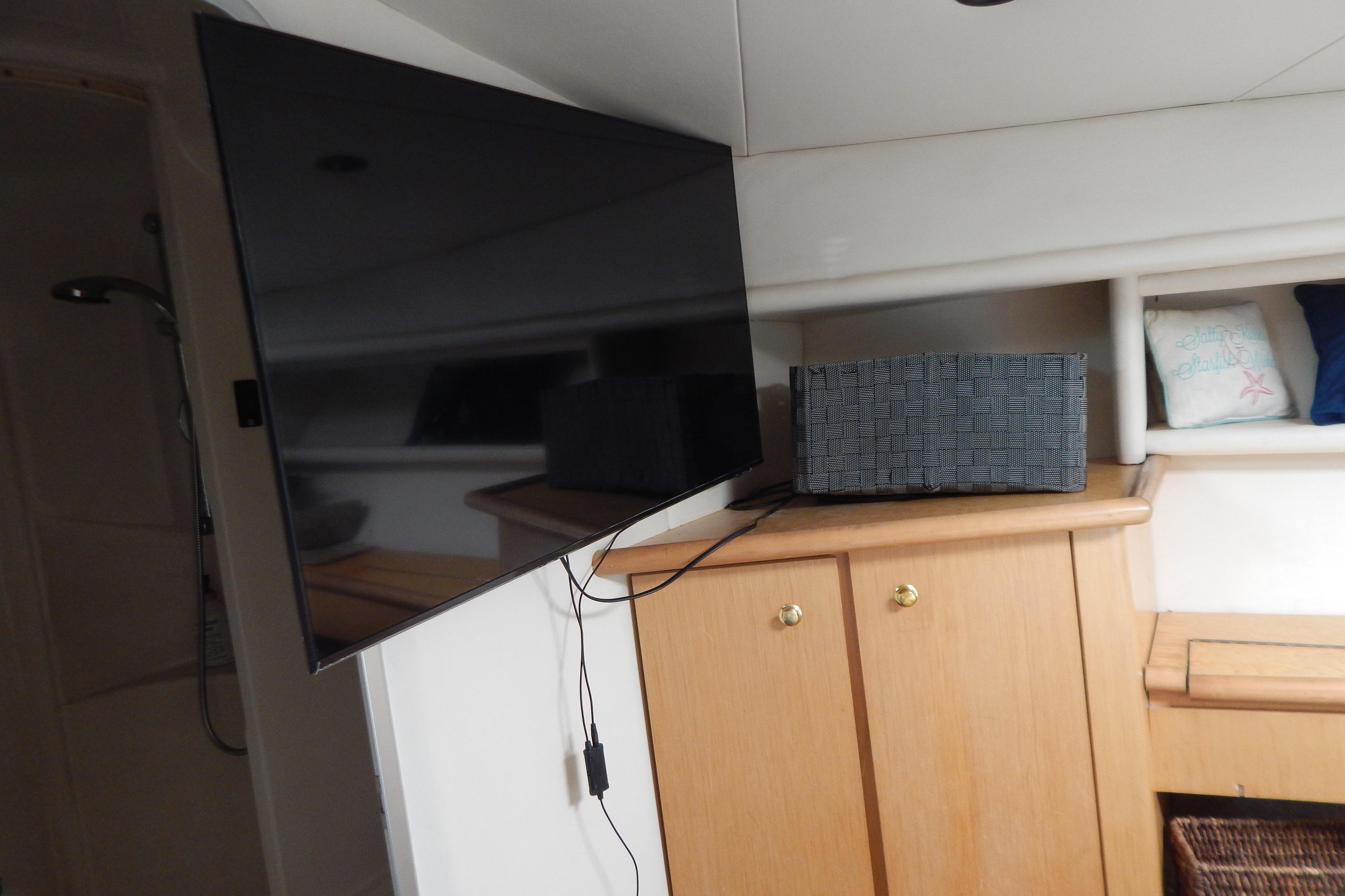 Flat-screen TV in a 1998 Magnum 4100 SCR yacht interior, with wooden cabinetry and decorative pillows.