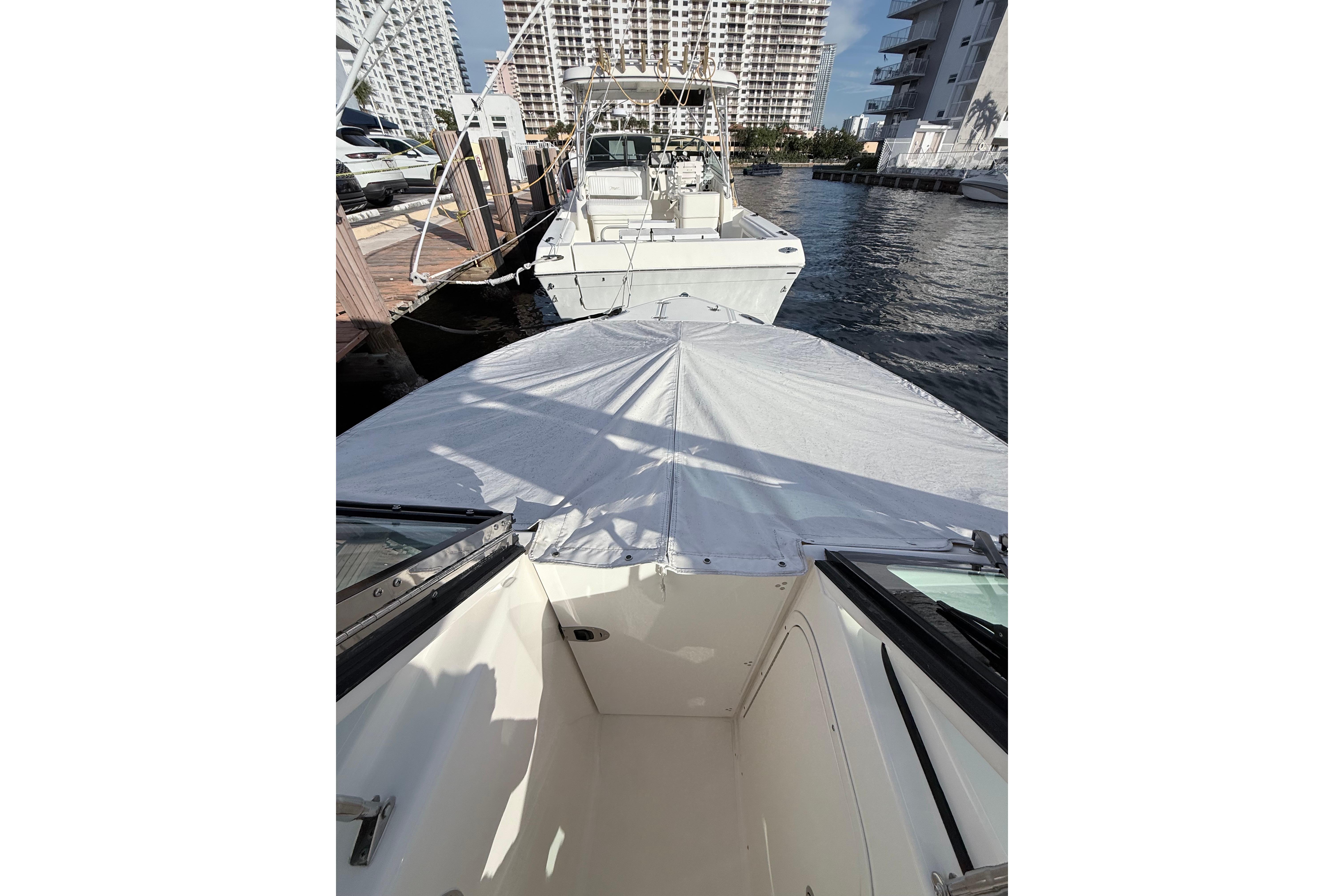 2022 Pursuit DC 266 Dual Console boat docked at marina, covered bow, cityscape background.