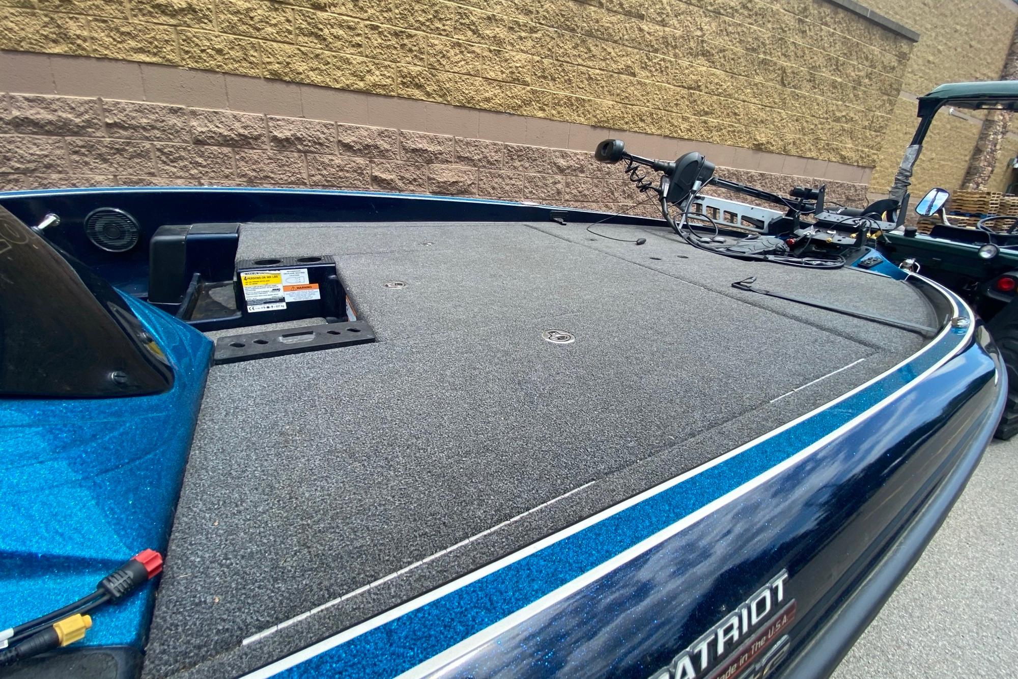 2020 Triton 20 TrX Patriot boat deck with trolling motor, parked near a brick wall.