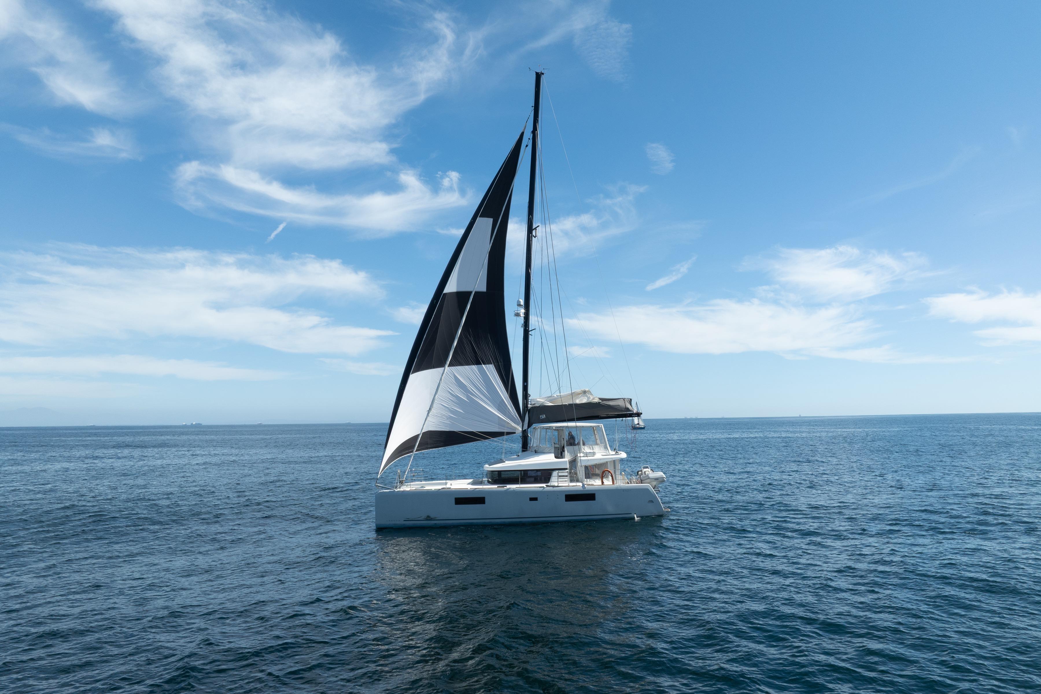2022 Lagoon 52 F catamaran sailing on open sea under clear blue sky.