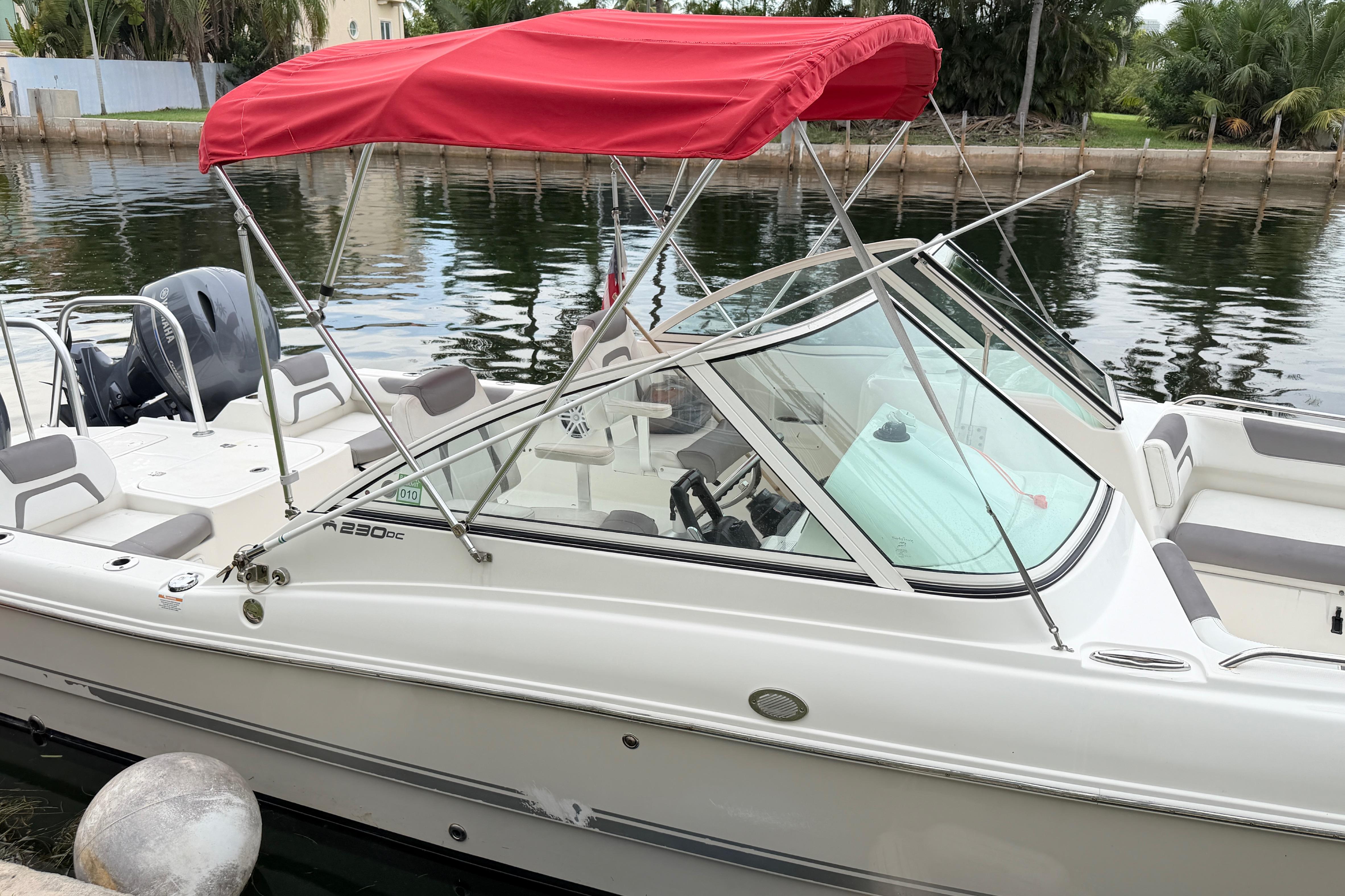 2019 World Cat 230 DC boat with red canopy docked by a canal.