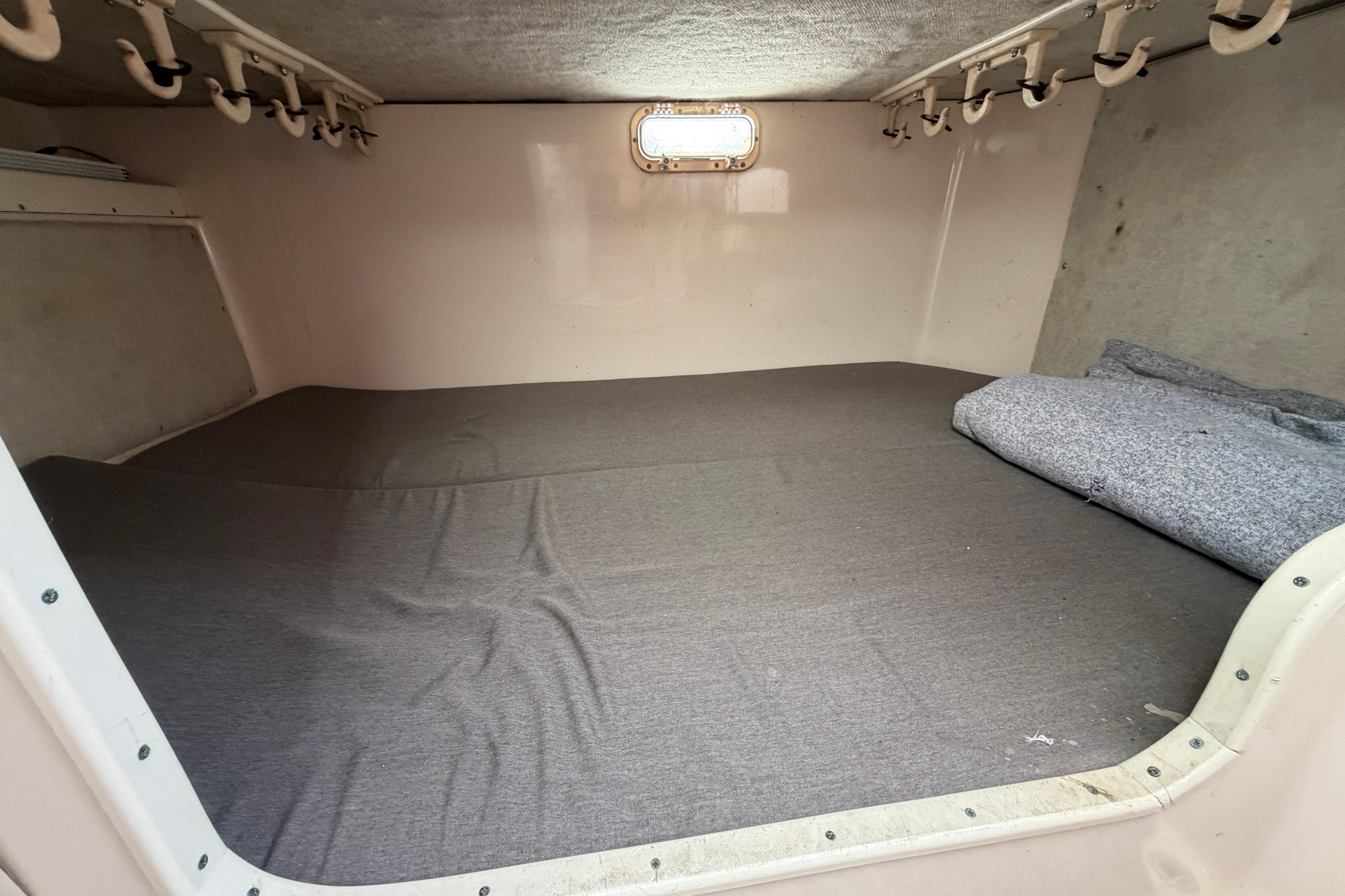 1996 Grady-White Marlin 300 cabin interior with gray bedding and storage hooks.