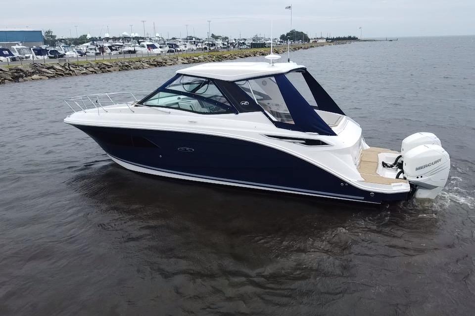 2021 Sea Ray Sundancer 320 Outboard cruising on calm waters near a marina.