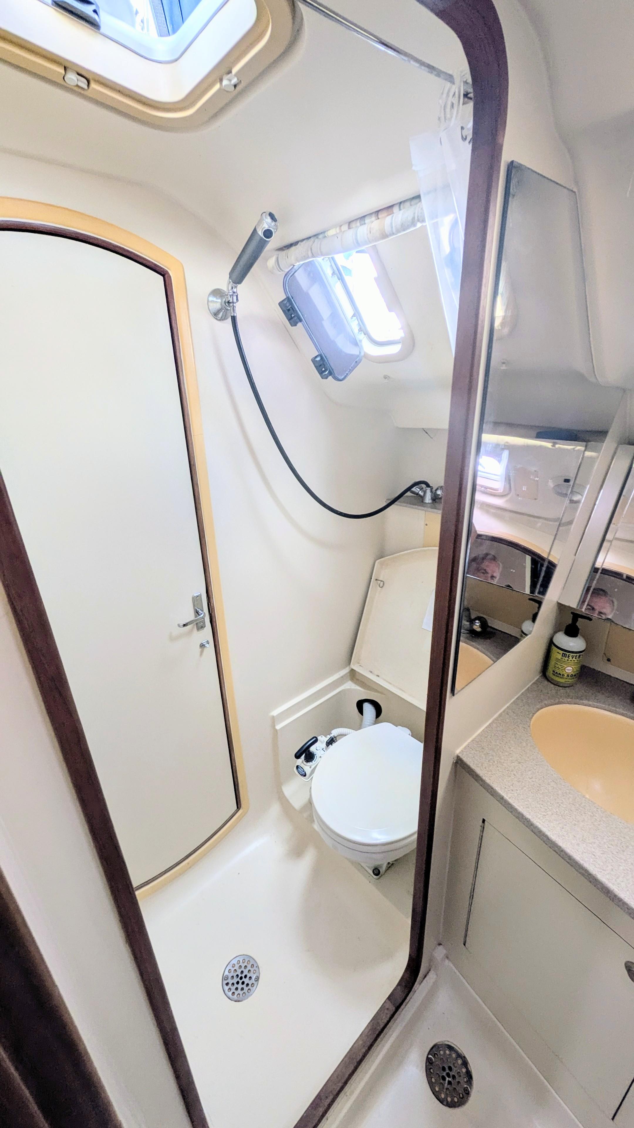 Compact bathroom in a 2001 Hunter 380 yacht, featuring a shower, toilet, and sink.