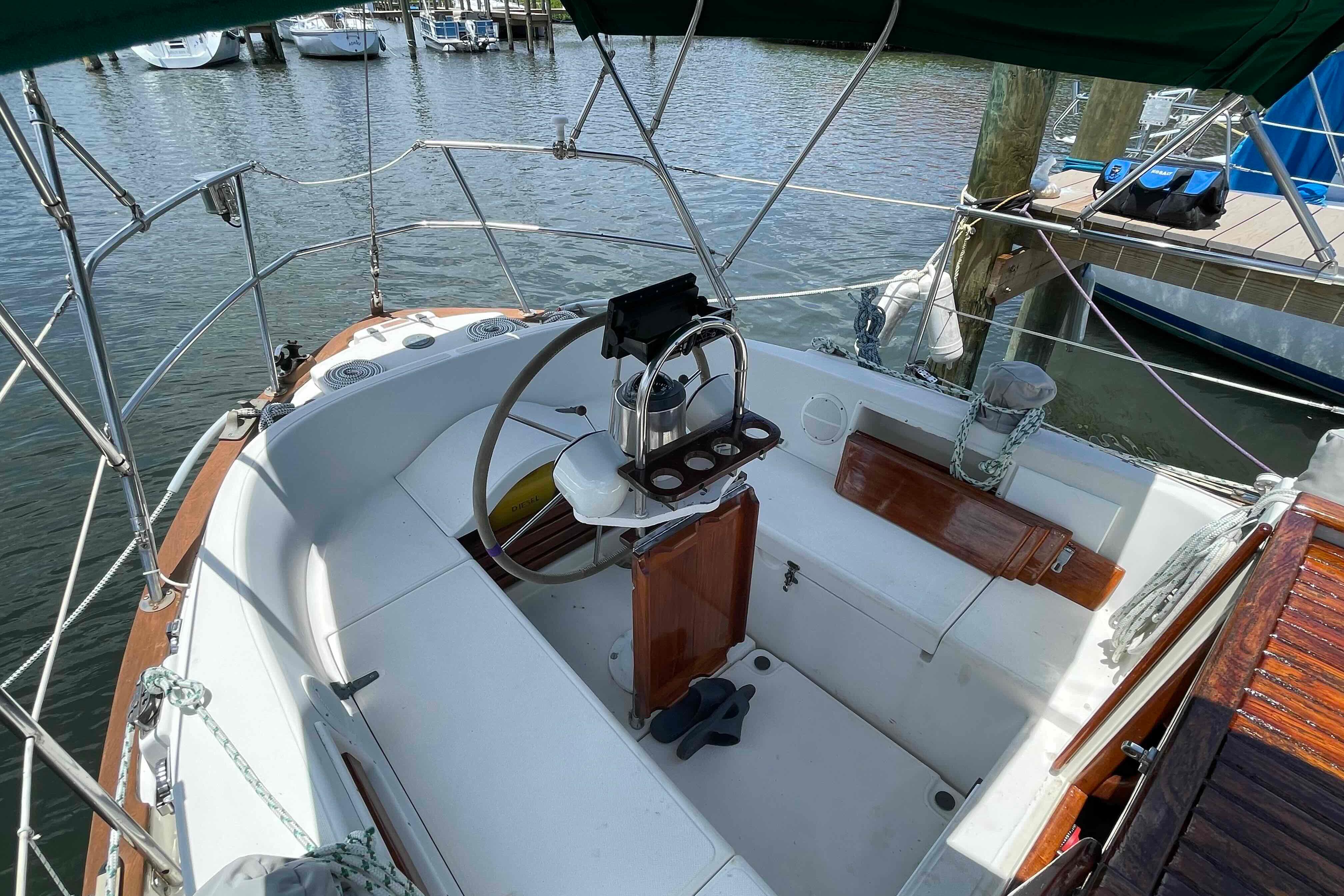 Cockpit of 1987 Pacific Seacraft 34 sailboat, featuring steering wheel and seating, docked at marina.