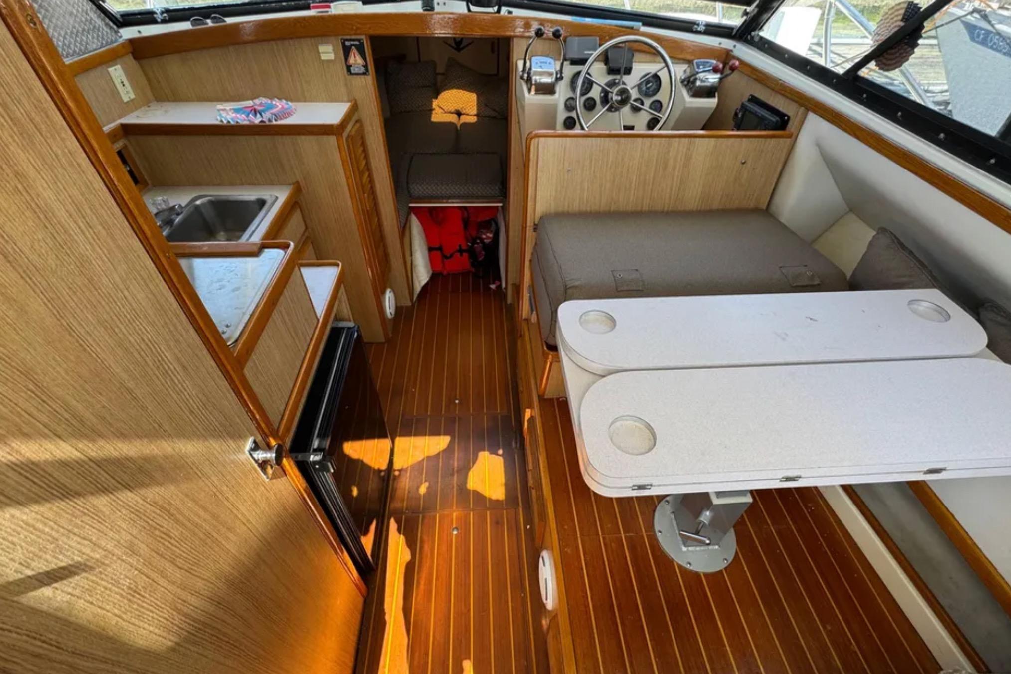 1988 Bertram 28 Sport Fisherman interior with wood finish, kitchenette, and seating area.