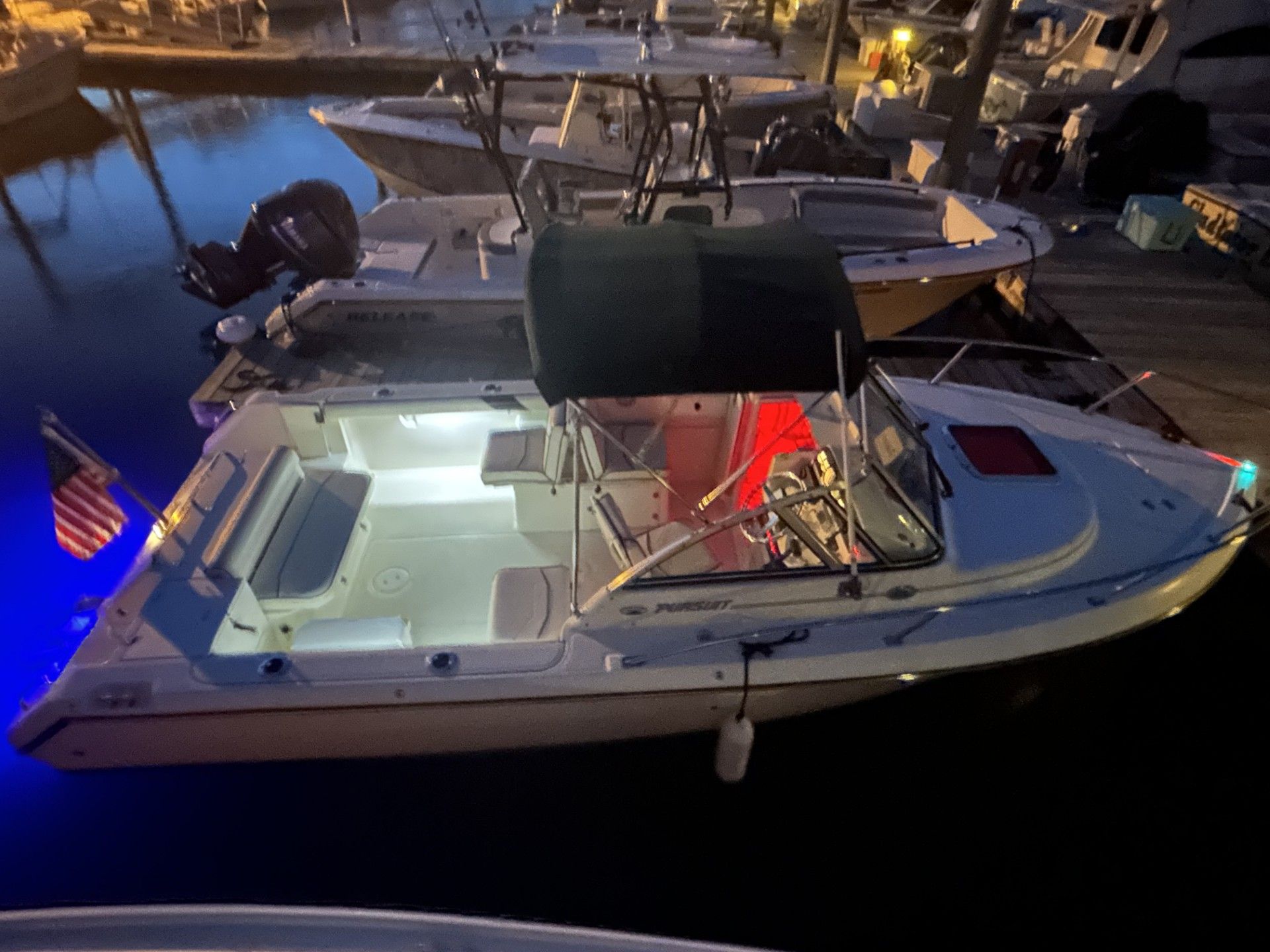1999 Pursuit Denali boat docked at night with lights.
