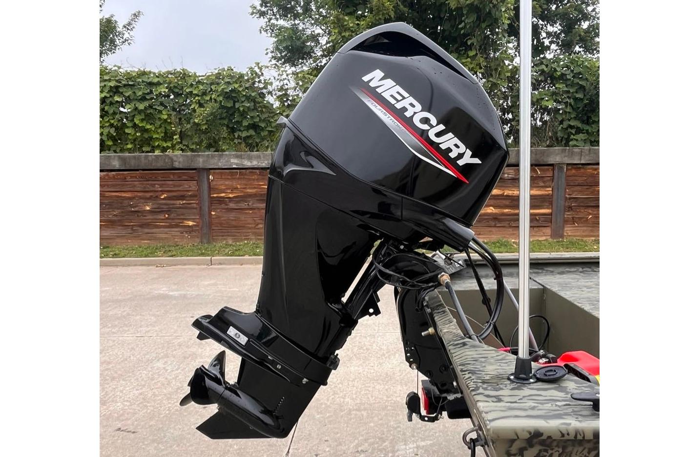 Outboard motor on 2026 Tracker Grizzly 1648 SC boat, parked outdoors.