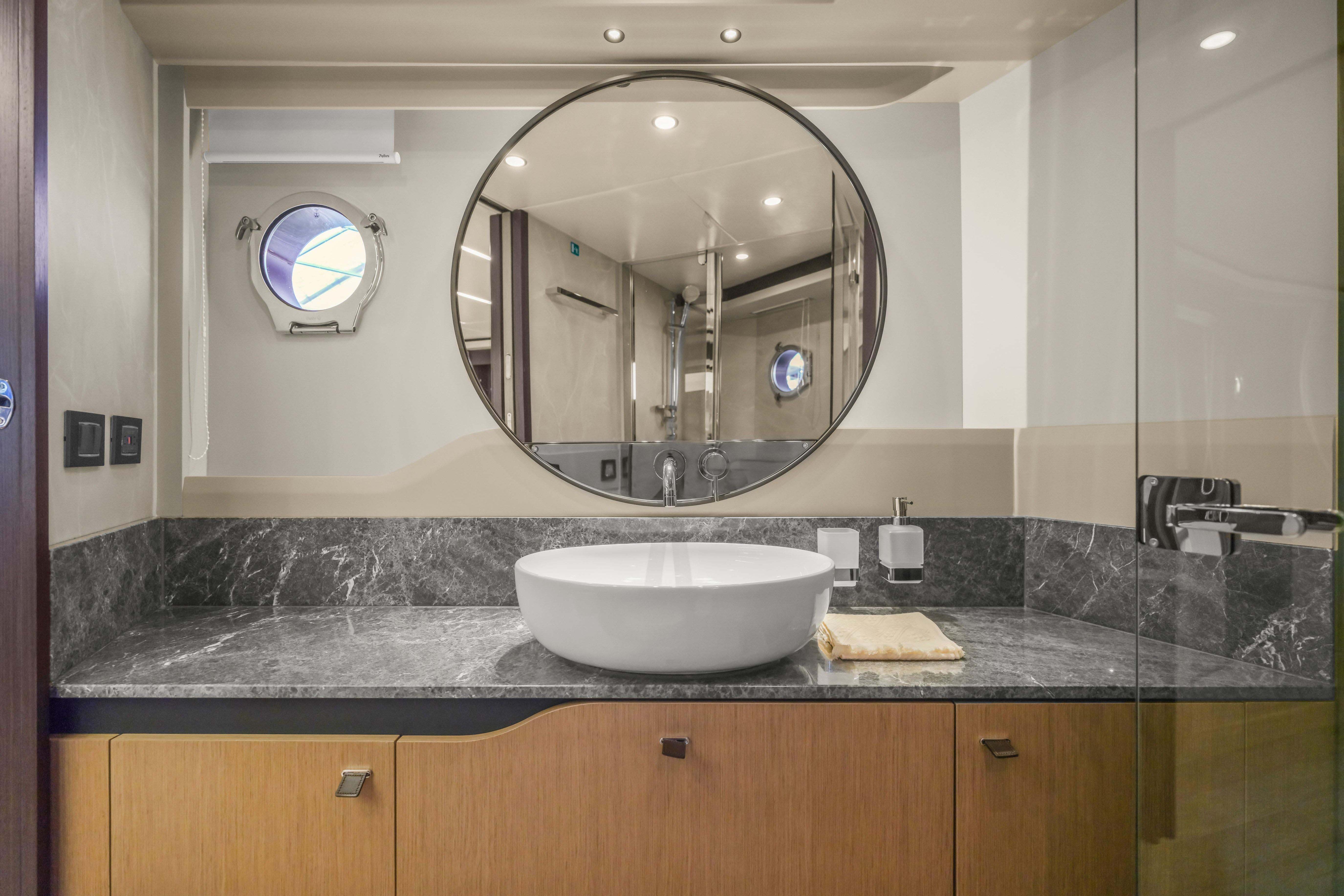Luxurious bathroom on 2026 Absolute 52 Fly yacht with modern sink and round mirror.