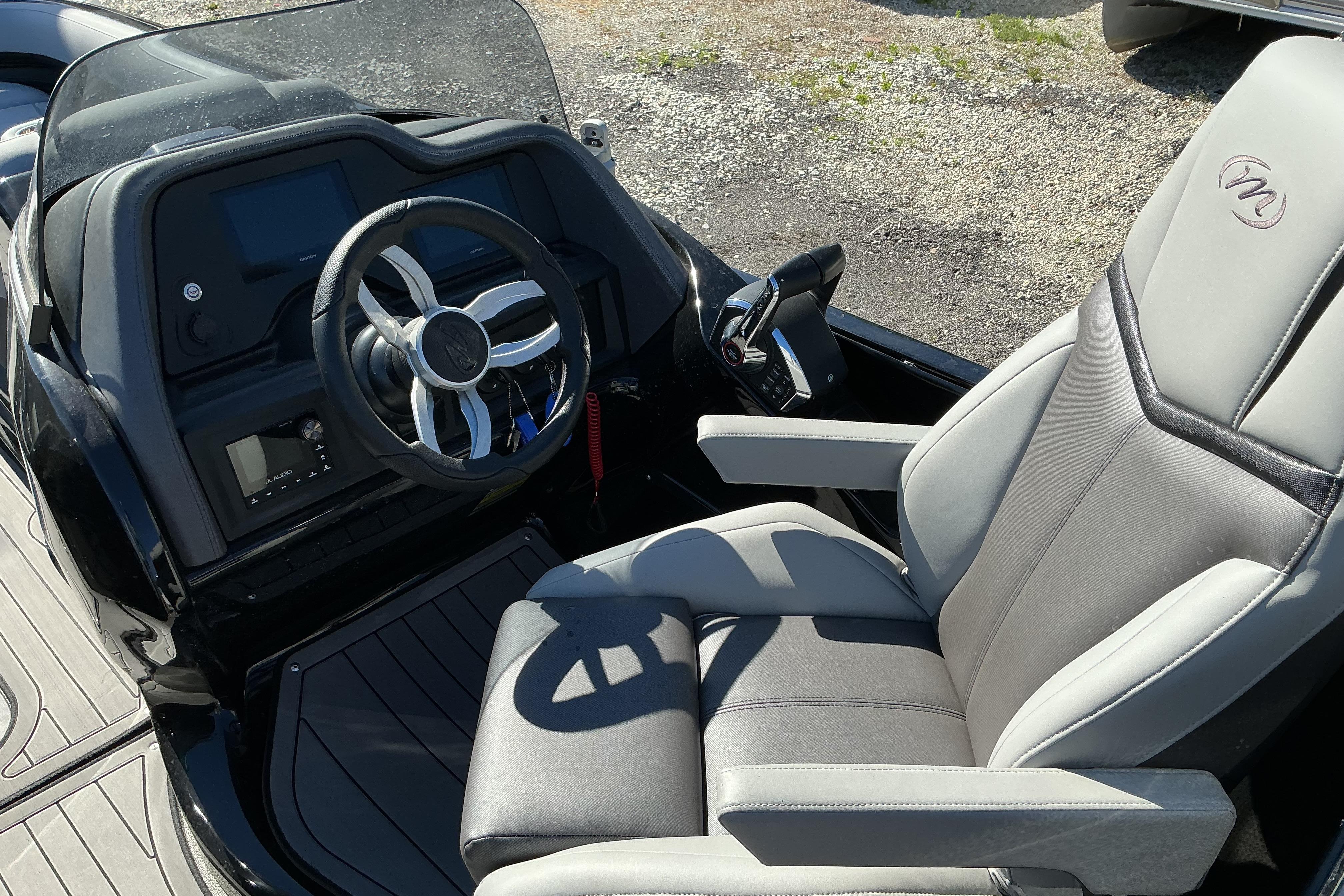 2024 Manitou 25 X-Plode XT SRS boat cockpit with steering wheel and captain's chair.