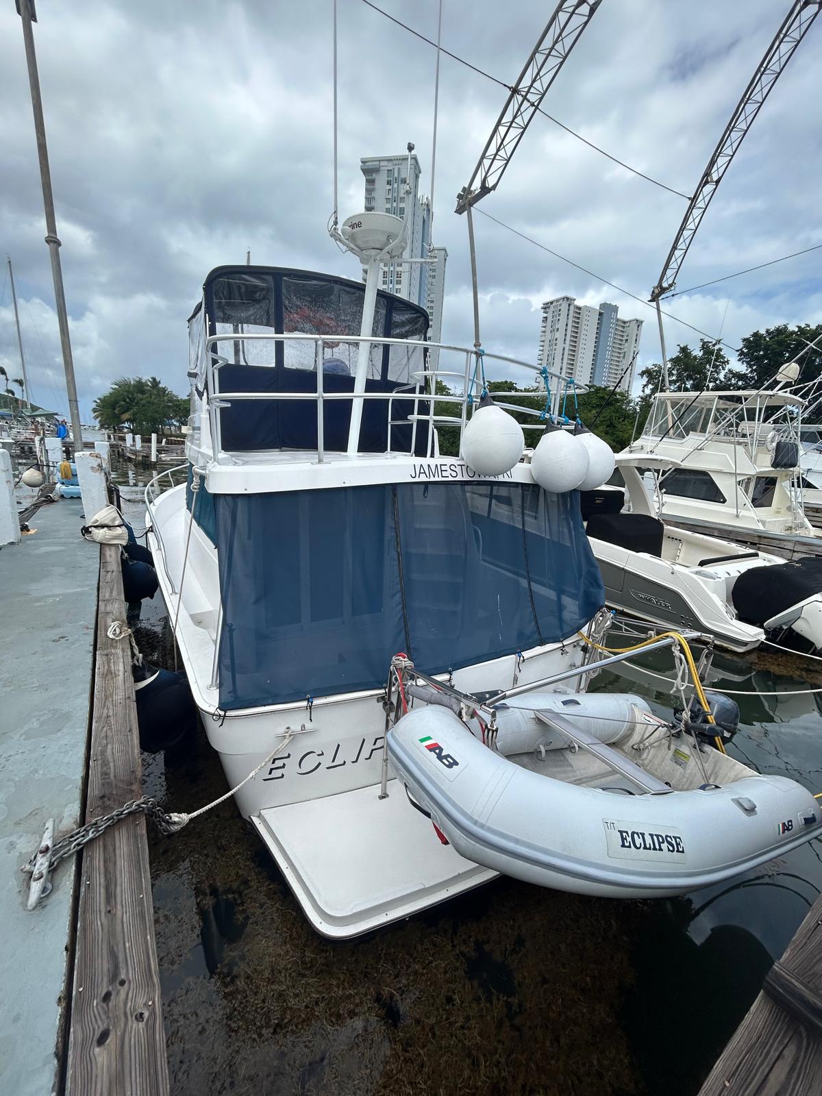 1999 Mainship 350 Trawler docked with inflatable boat, marina background.