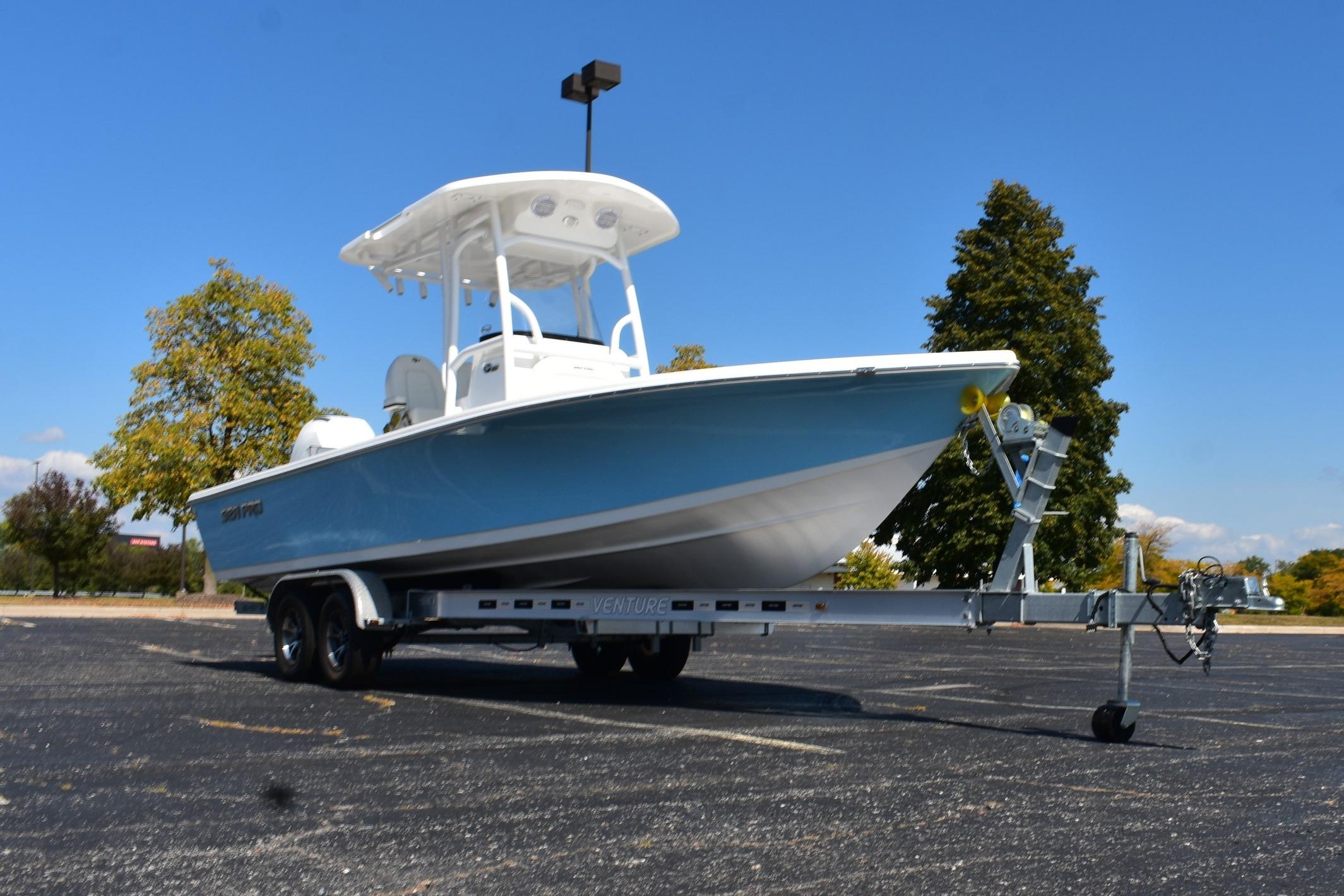 2025 Sea Pro 230 Bay boat on trailer in parking lot, clear blue sky.
