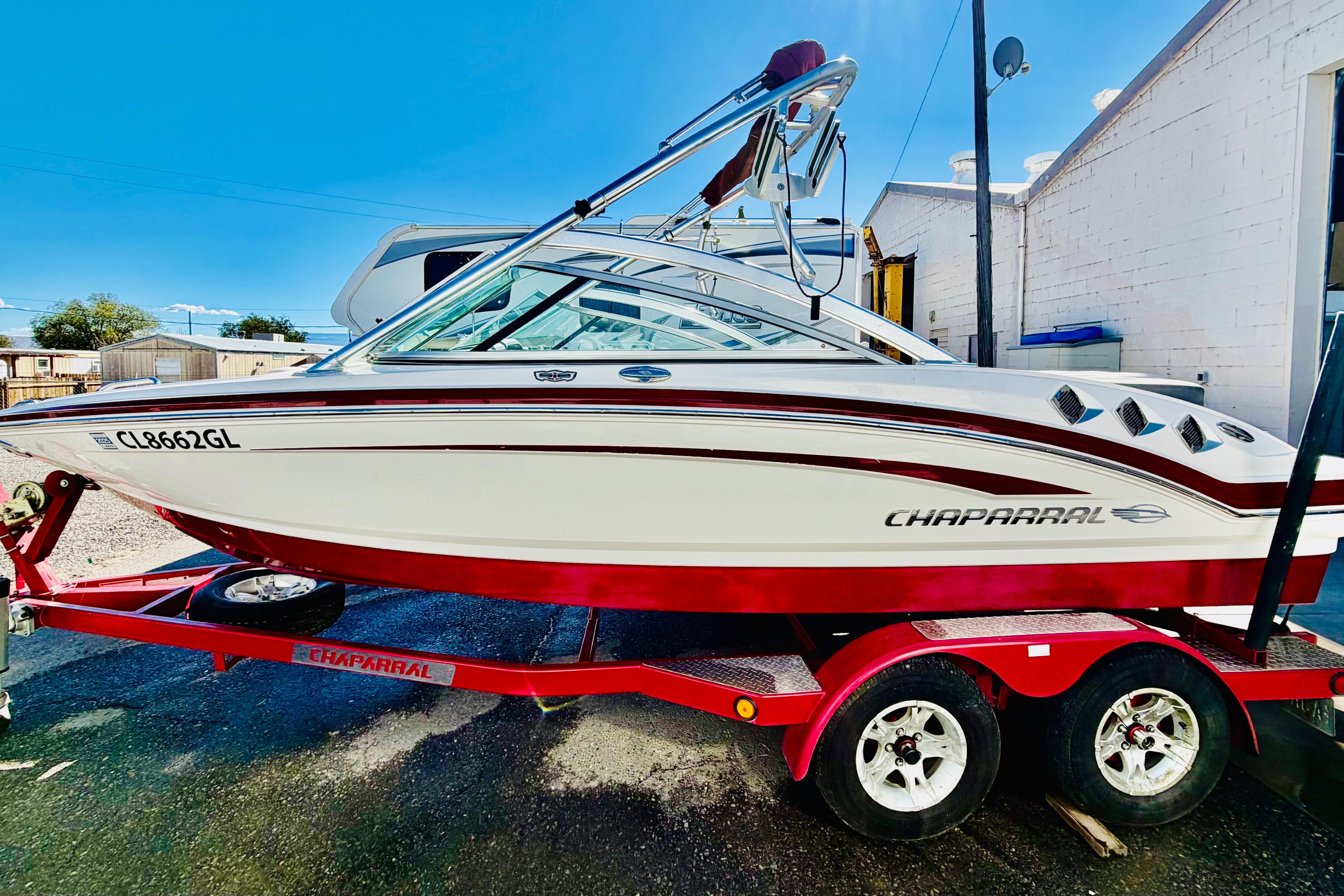 2013 Chaparral 206 SSi boat on red trailer, parked outdoors.