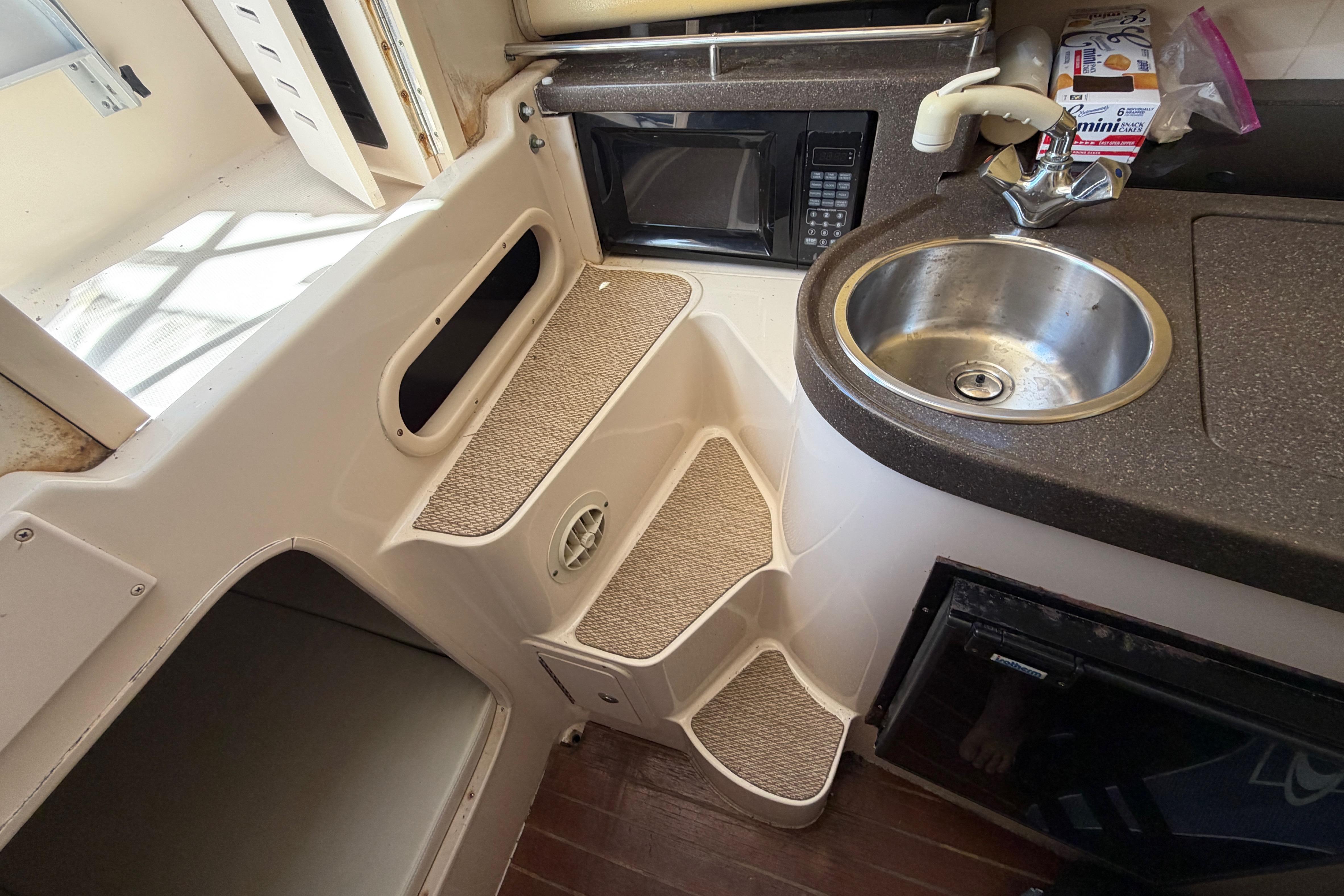 2006 Grady-White Sailfish 282 boat interior with kitchenette, sink, microwave, and steps.