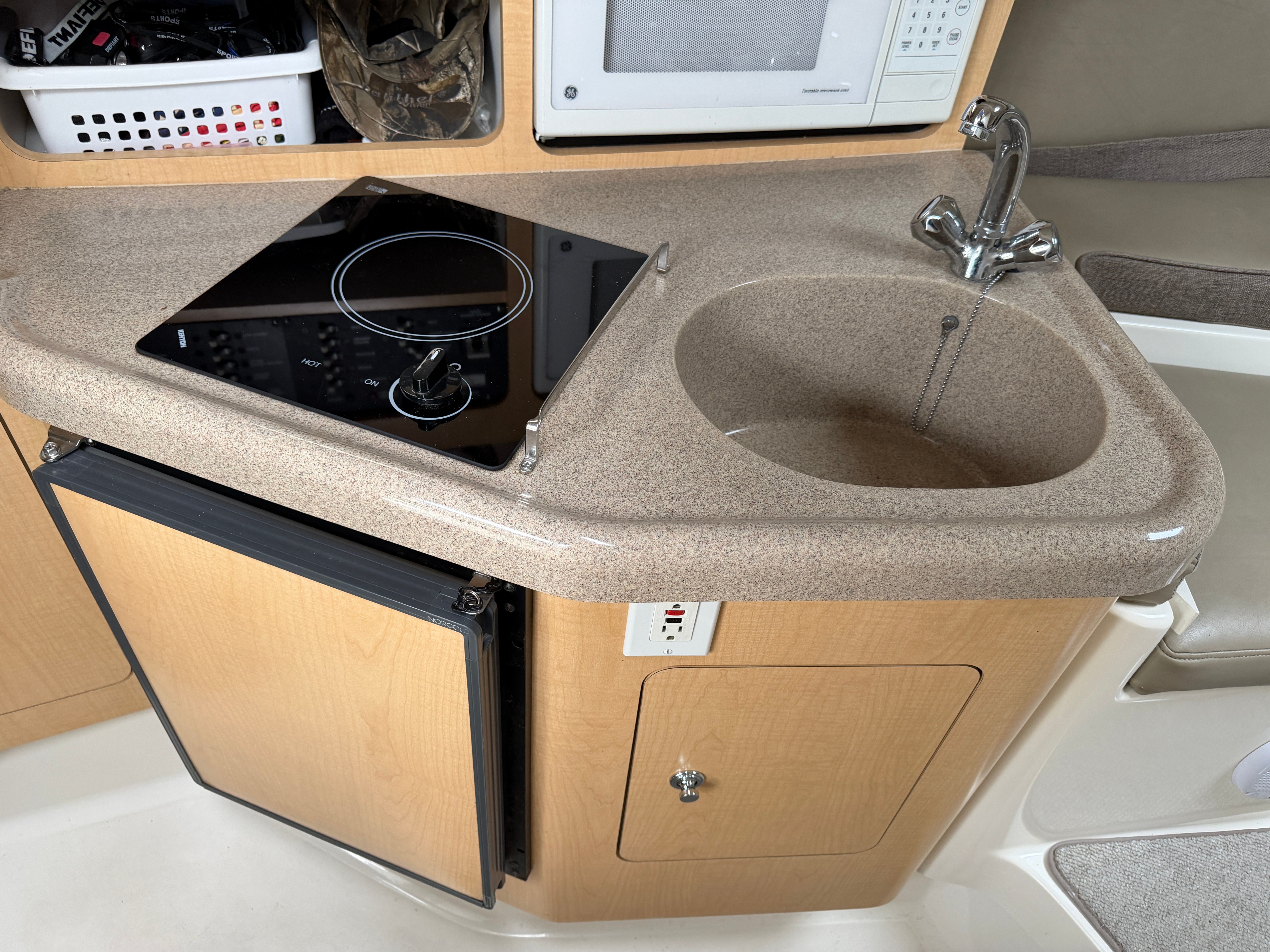 Compact kitchenette with sink, stove, and fridge in a boat.
