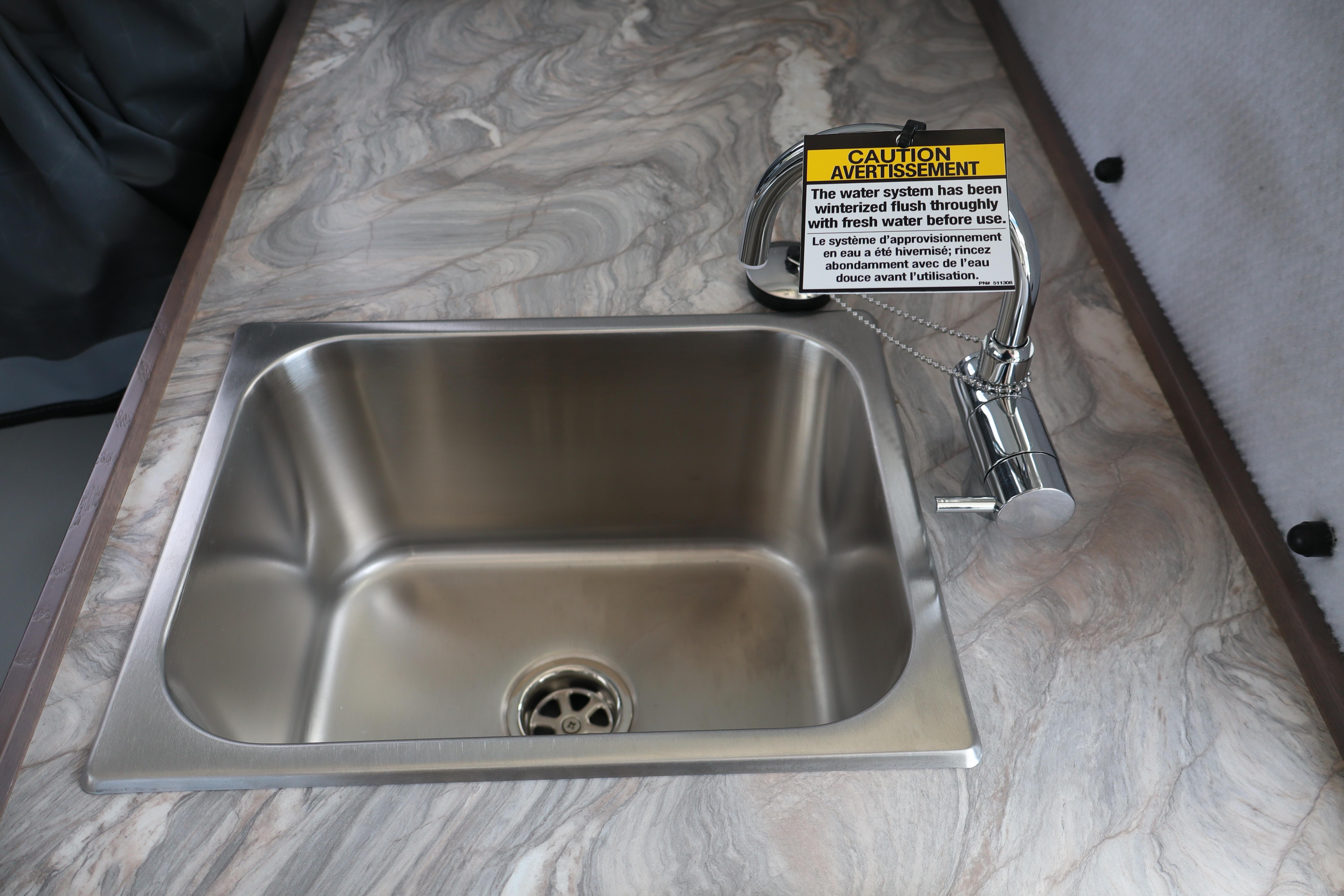 Stainless steel sink with caution sign in 2026 KingFisher 25 XAC boat kitchen.