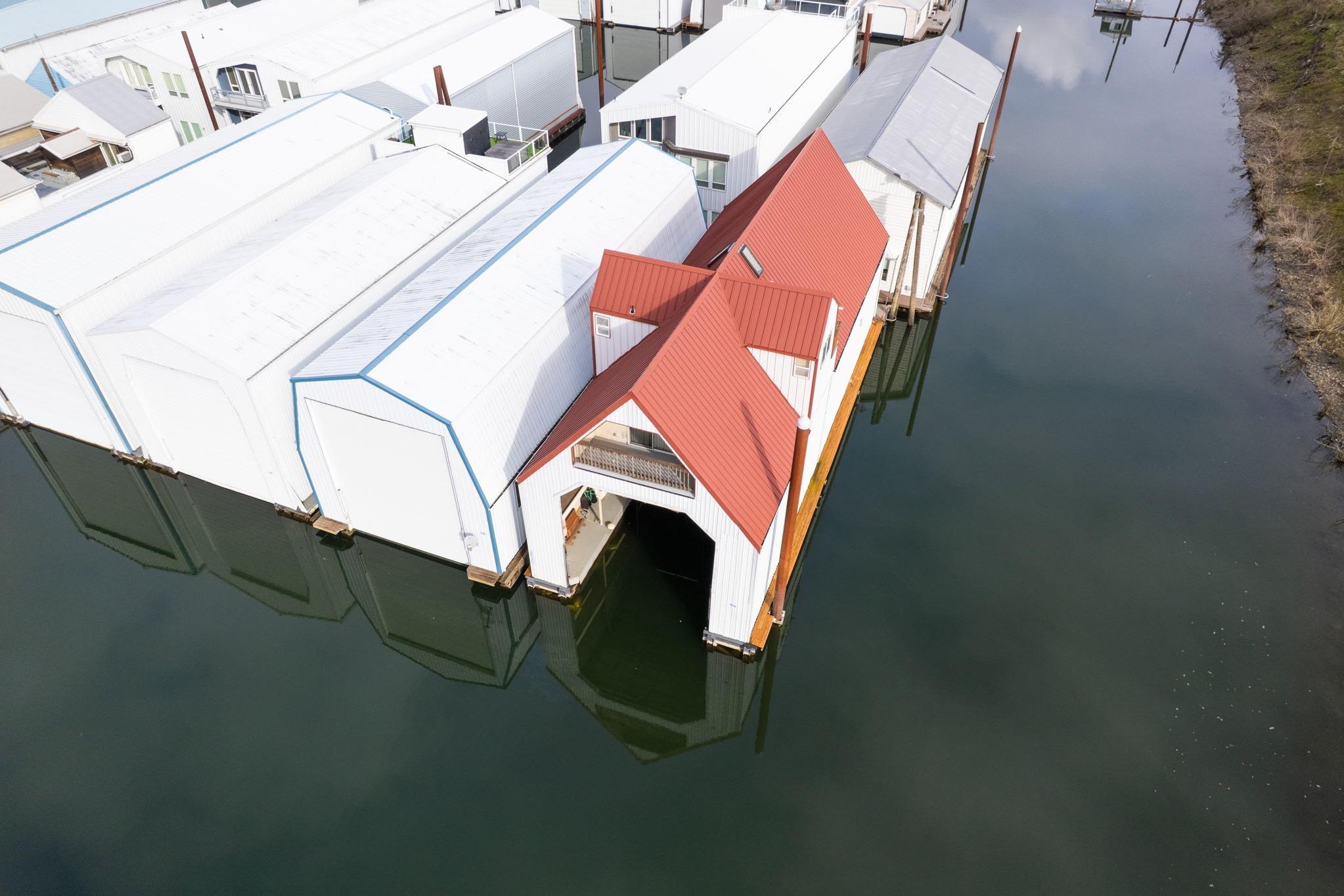 Aerial view of a 1976 custom boathouse with a red roof on calm water.