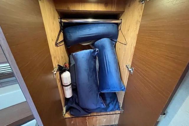 Storage cabinet in 2016 Sea Ray Sundancer 510 with blue cushions and fire extinguisher.