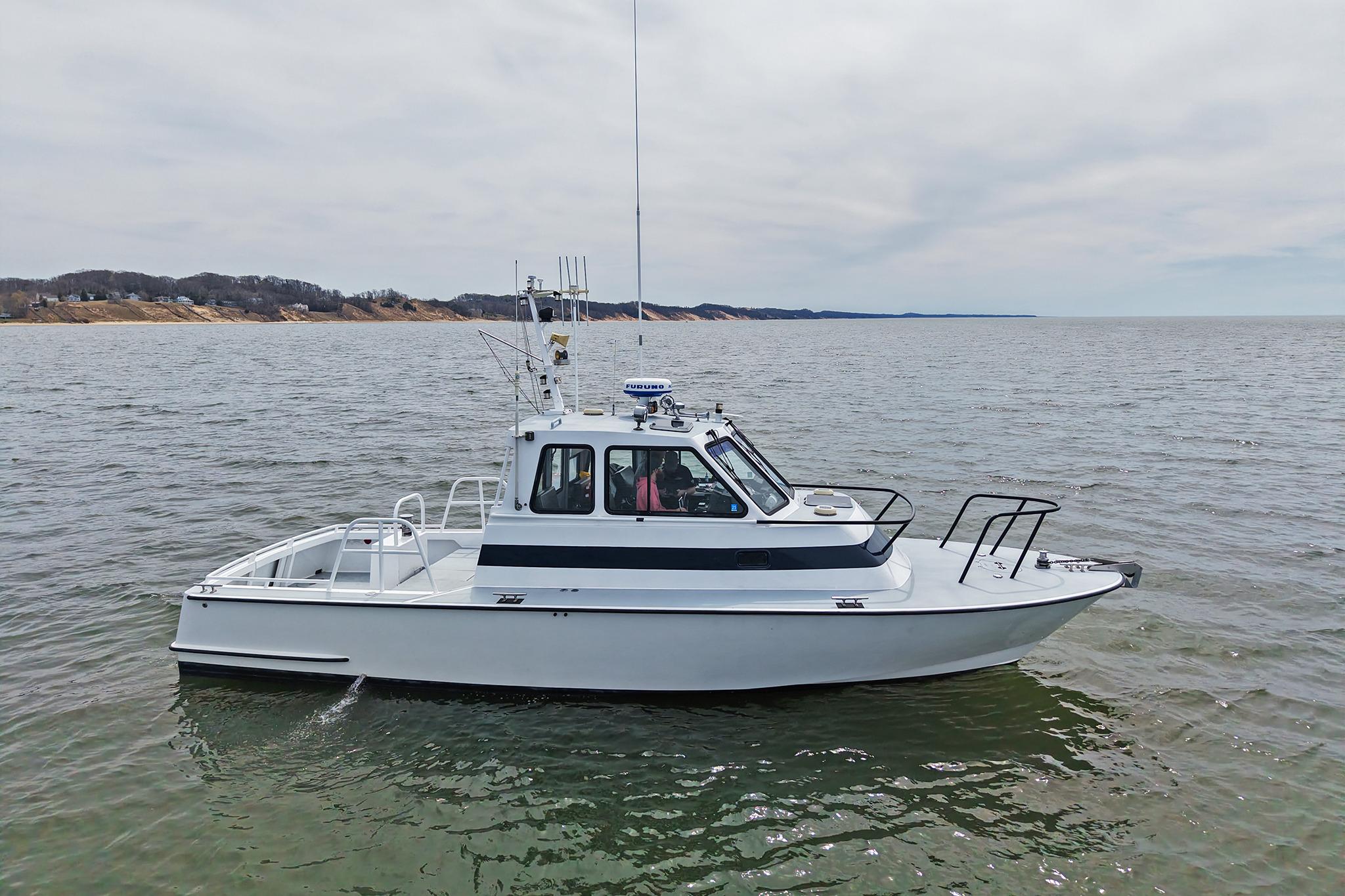1990 Boston Whaler 36 Defiance boat on calm waters, coastal background.