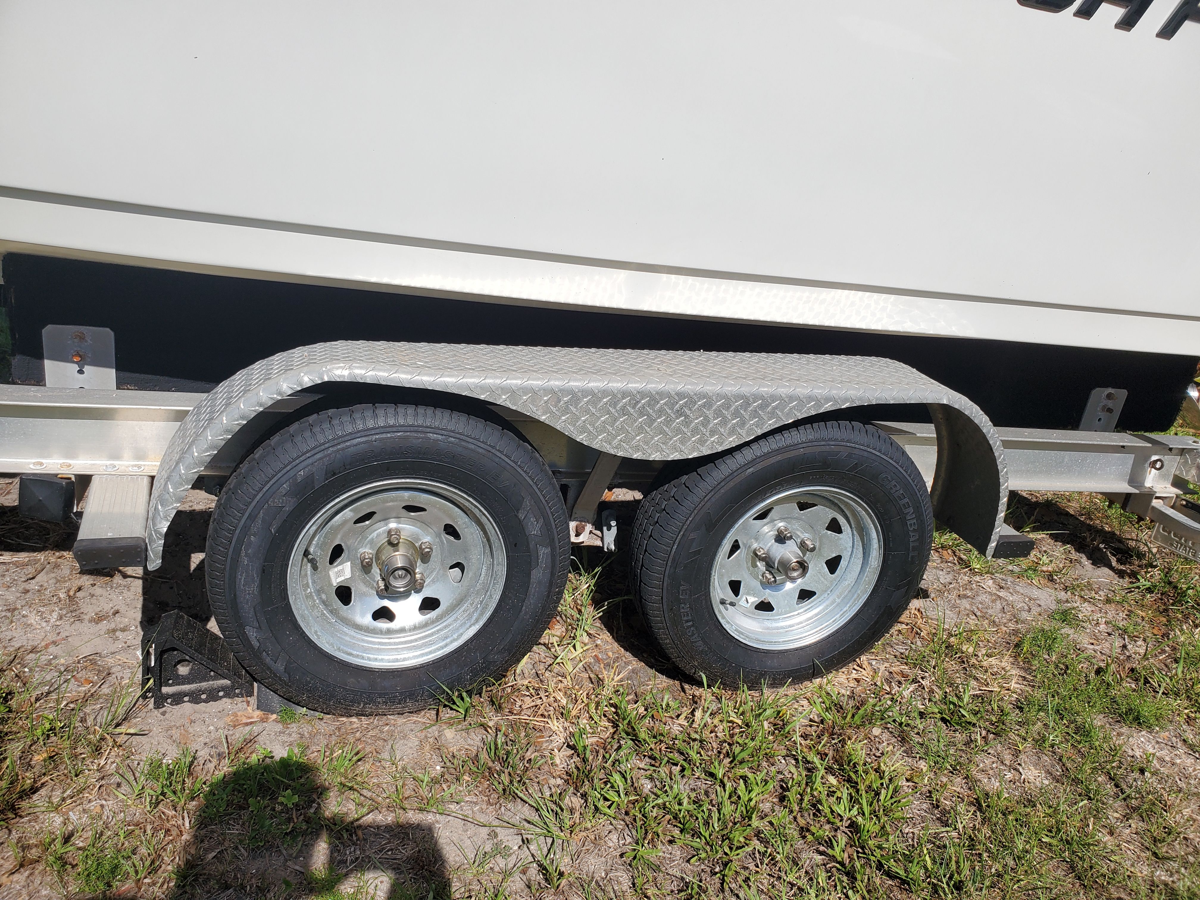 A boat trailer with two wheels on grass.