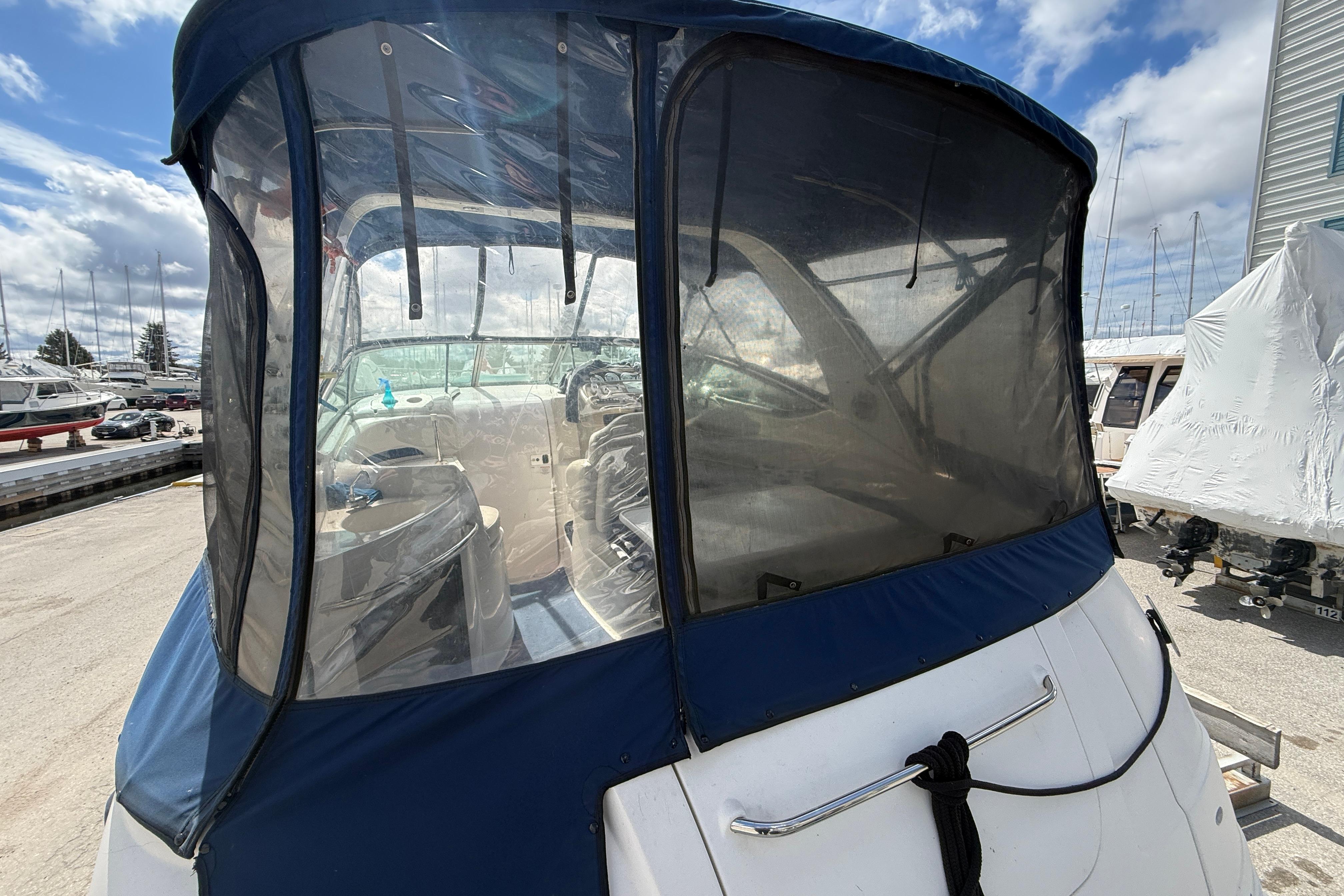 2003 Chaparral Signature 280 boat with blue canopy in a marina setting.