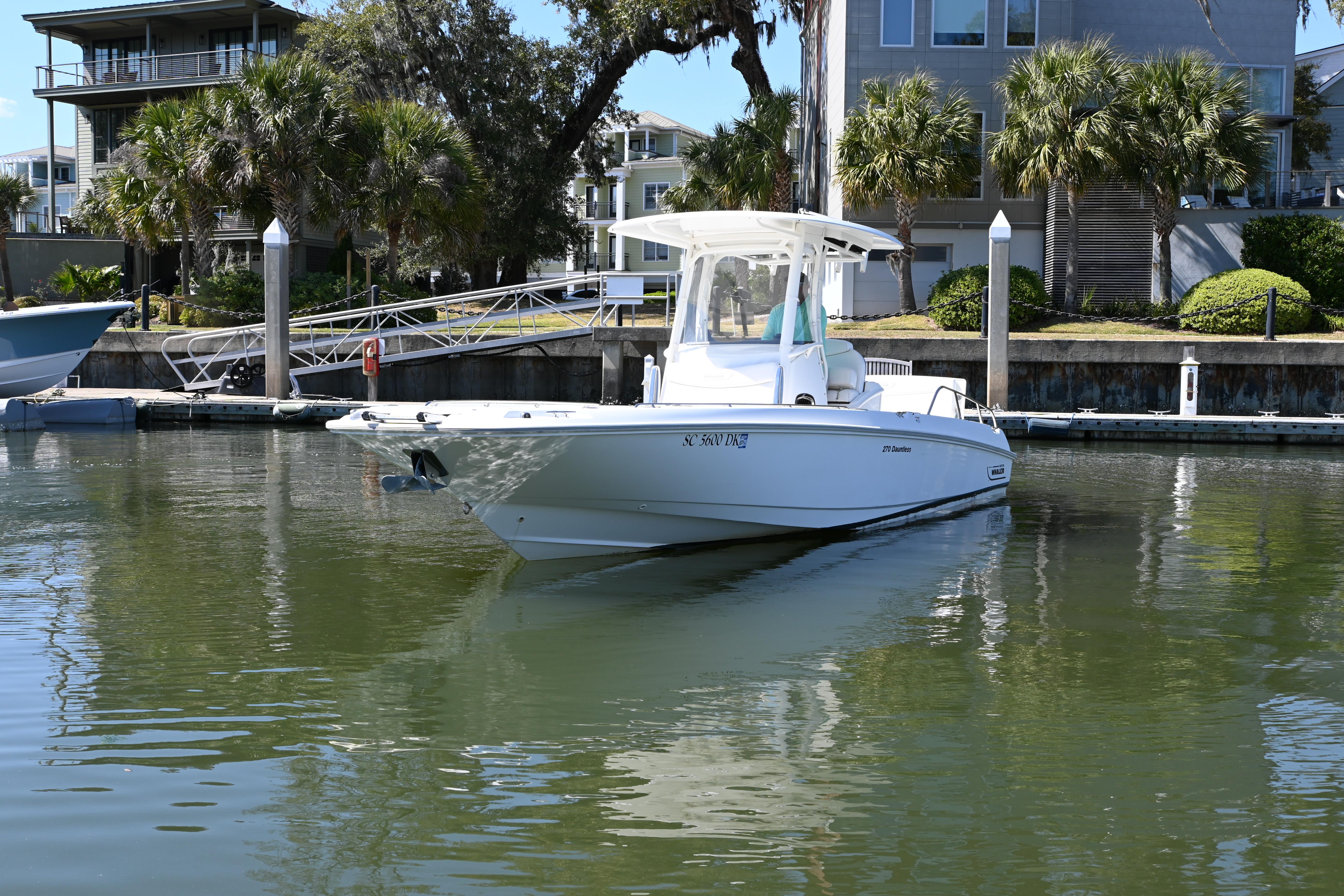 2014 Boston Whaler 270 Dauntless boat docked in a serene marina setting.