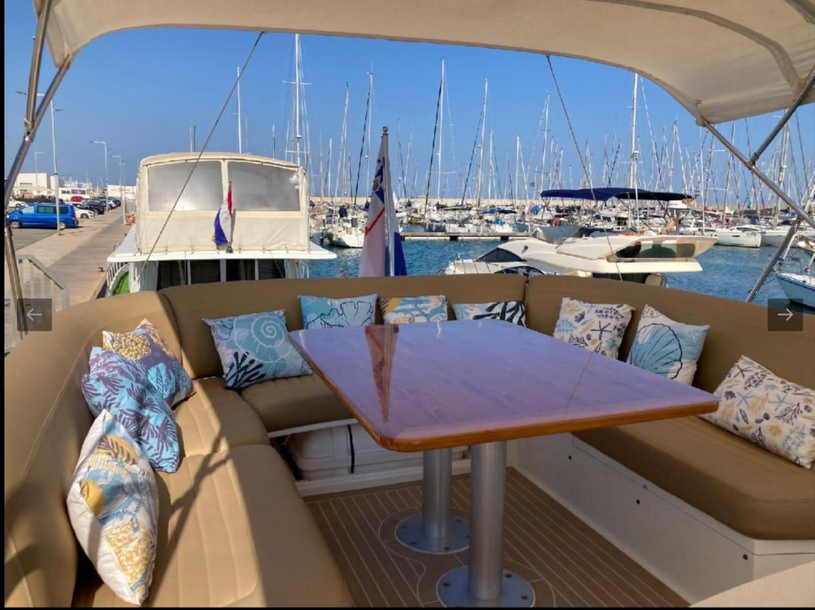 Luxurious 2005 Sealine T60 yacht with cushioned seating and table, docked at a marina.