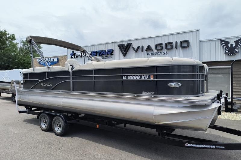 2017 Manitou 25 Oasis SE pontoon boat on trailer at dealership.