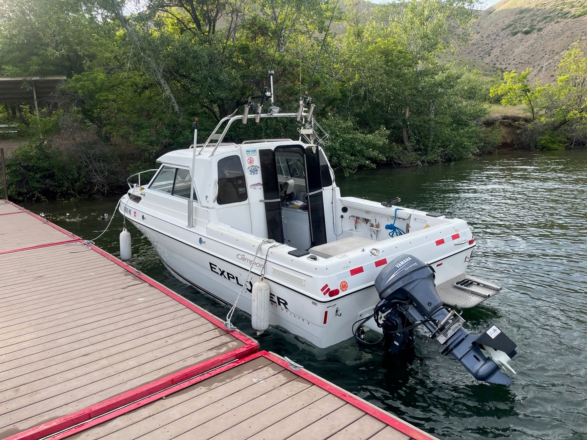A 2002 Campion 622 Explorer docked at a wooden pier in a wooded area.