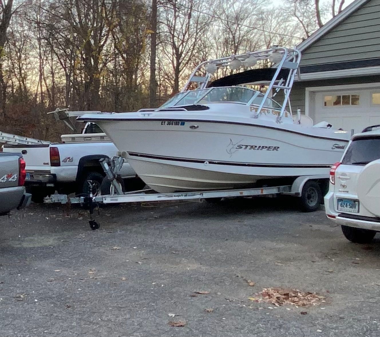 A 2002 Seaswirl Striper 2101 DC boat on a trailer, parked next to a house.