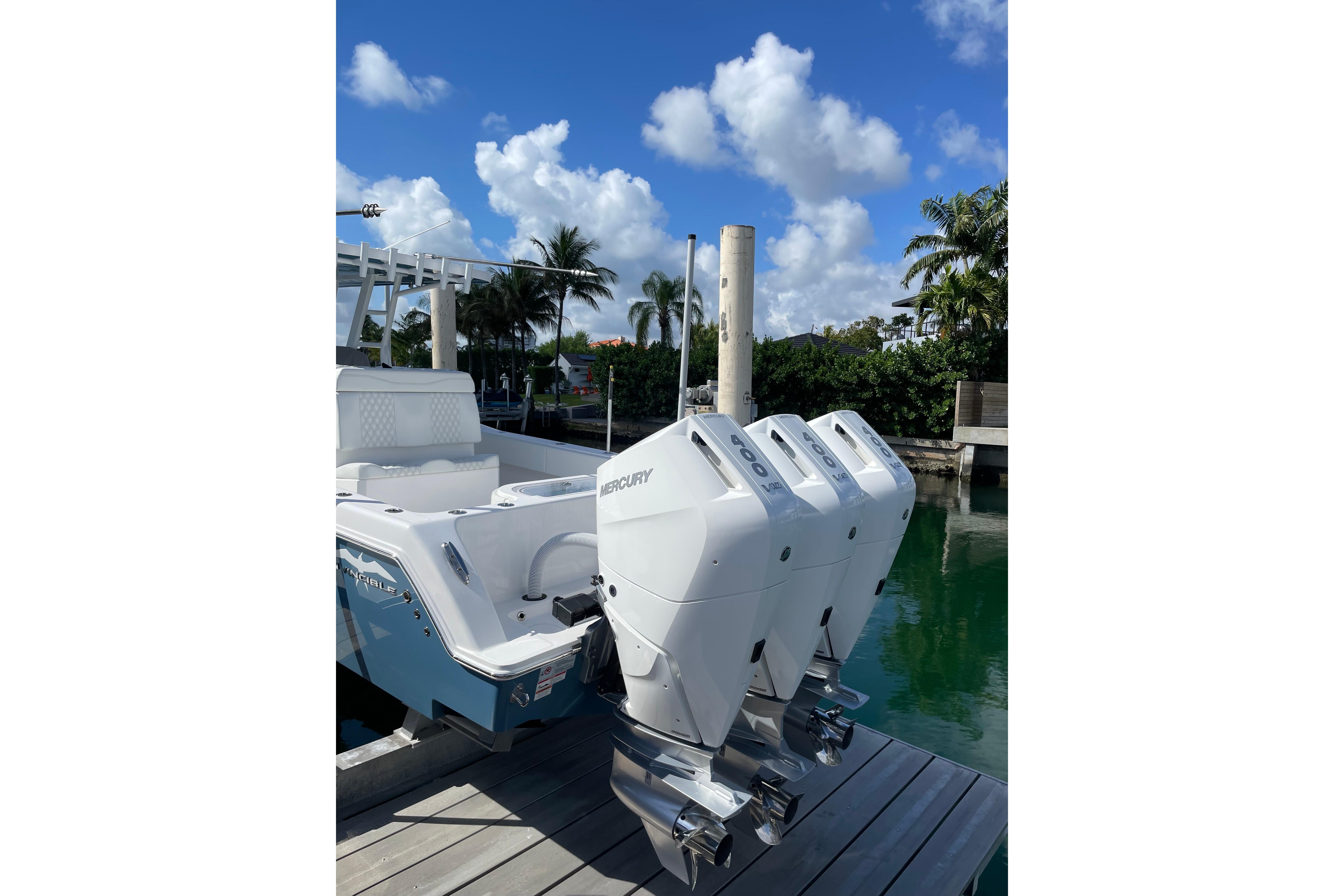 2024 Invincible 36 Open Fisherman with triple Mercury engines docked by palm trees.