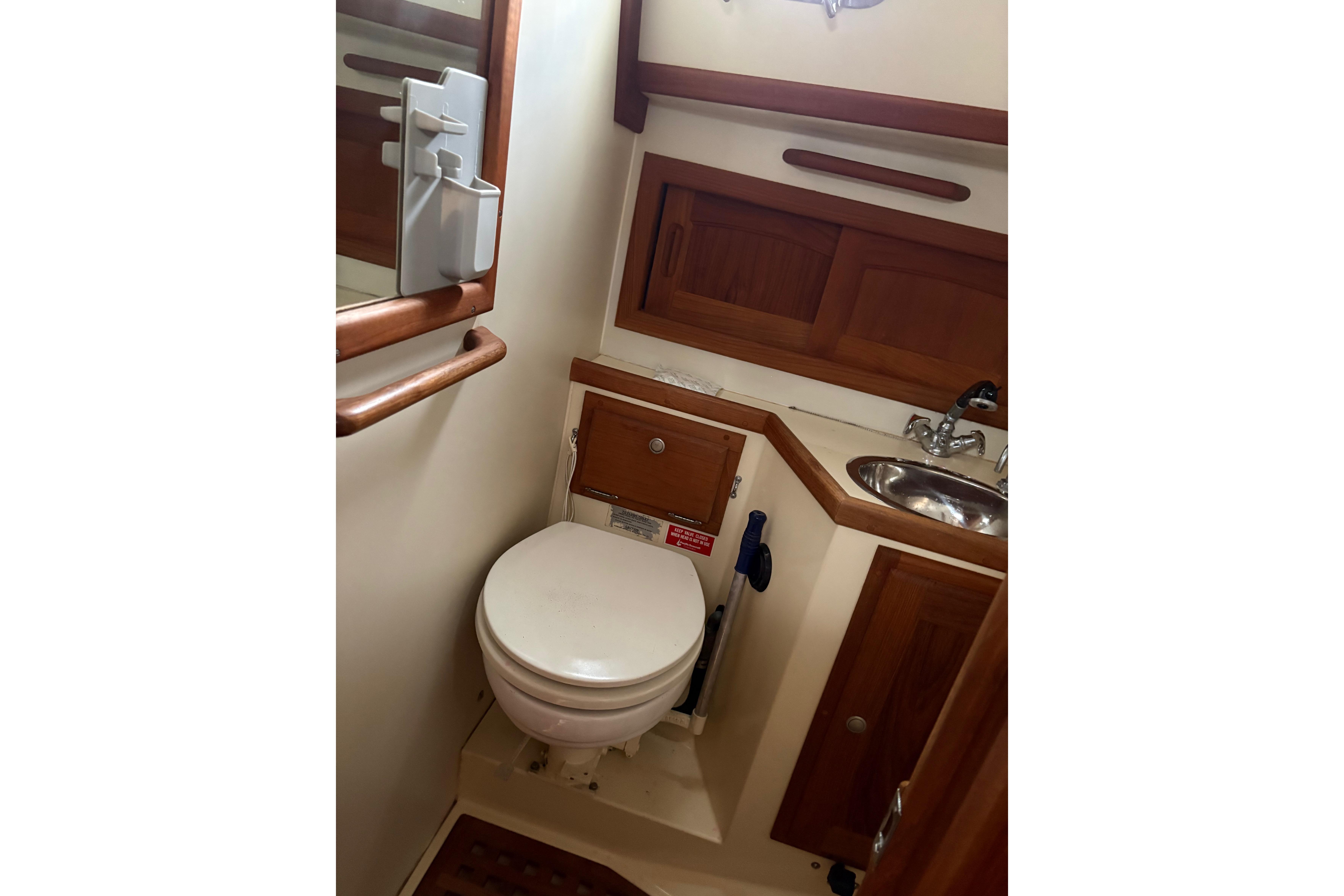 1997 Pacific Seacraft Crealock 34 yacht bathroom with toilet, sink, and wooden cabinetry.