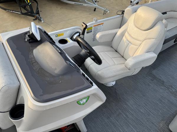 Captain's seat and console of 2022 Godfrey 2286 boat, featuring steering wheel and controls.