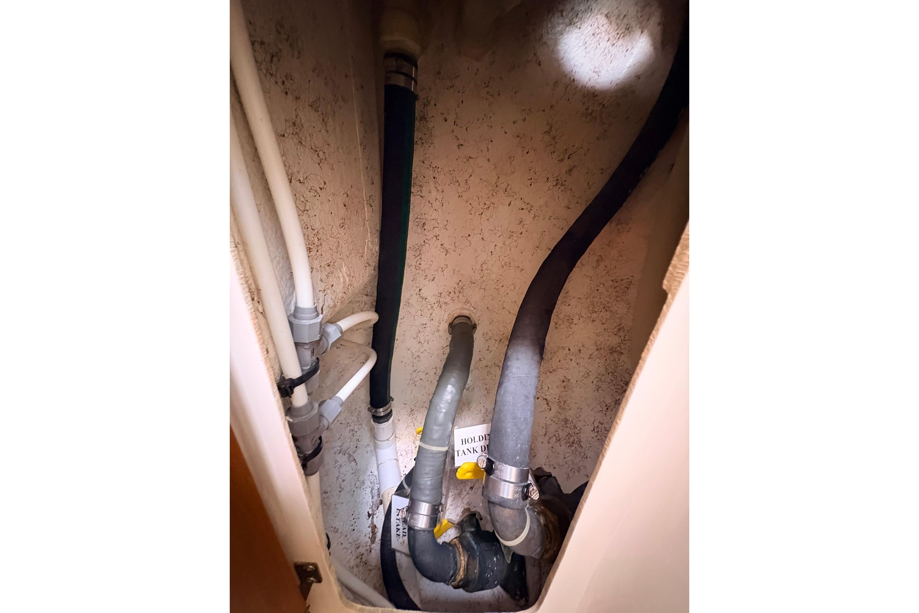 Plumbing system inside 2009 Caliber 40LRC SE boat, featuring various pipes and fittings.
