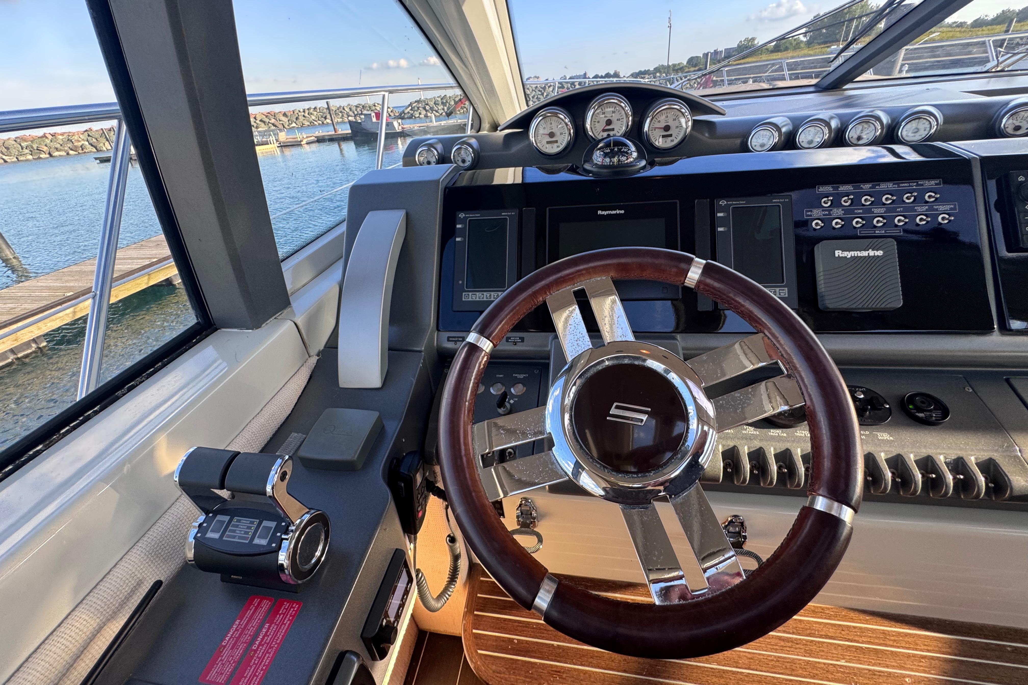 Steering wheel and dashboard of a 2006 Azimut 68S yacht, featuring modern navigation equipment.